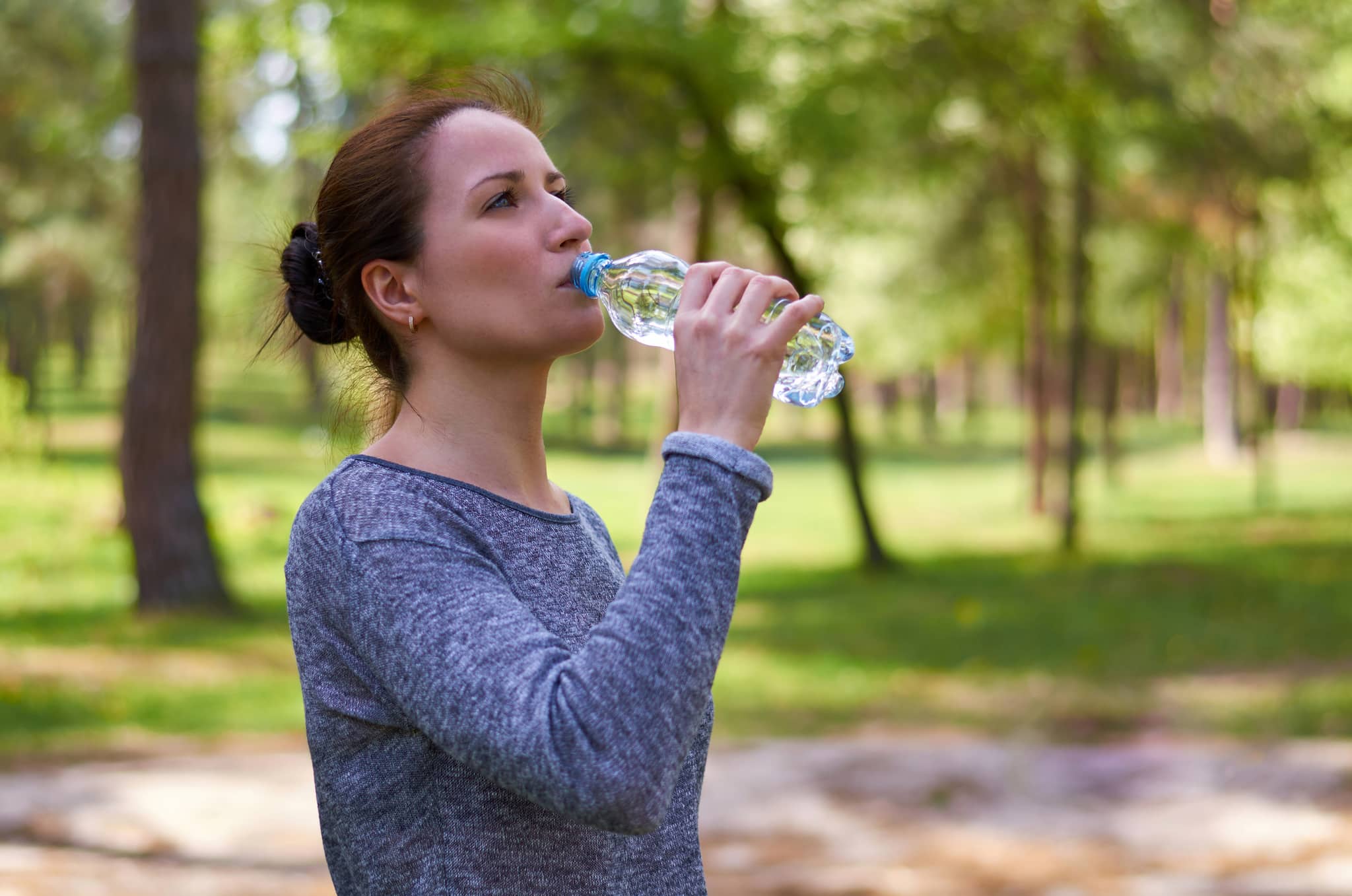 Frau trinkt draußen Wasser bei großer Hitze