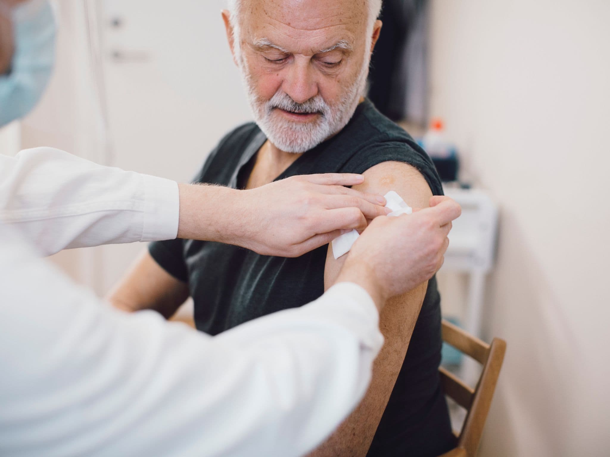 Ein älterer Mann wurde gegen Gürtelrose geimpft und bekommt ein Pflaster auf den Oberarm.
