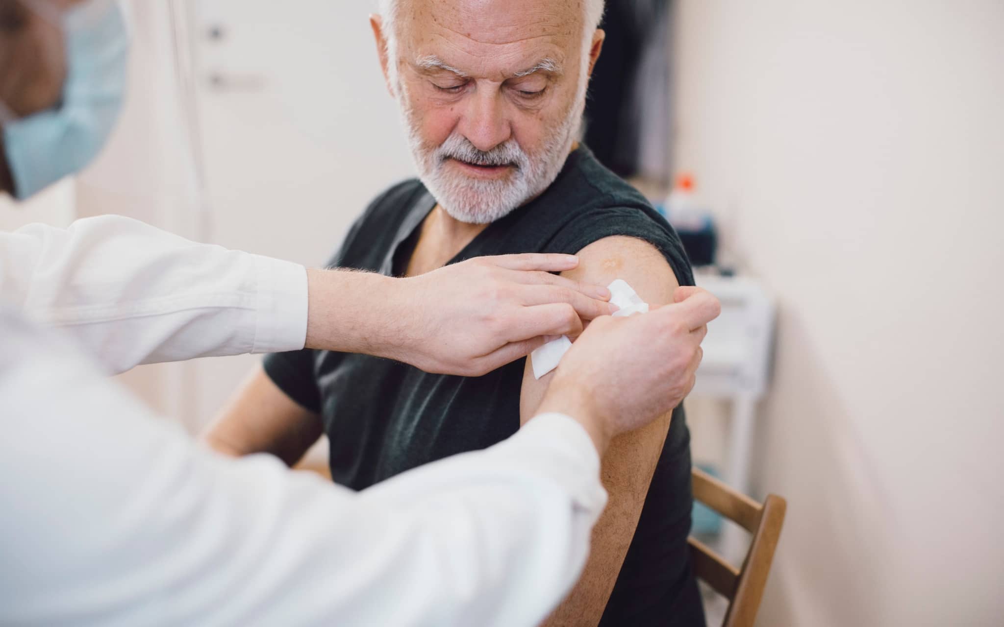 Ein älterer Mann wurde gegen Gürtelrose geimpft und bekommt ein Pflaster auf den Oberarm.