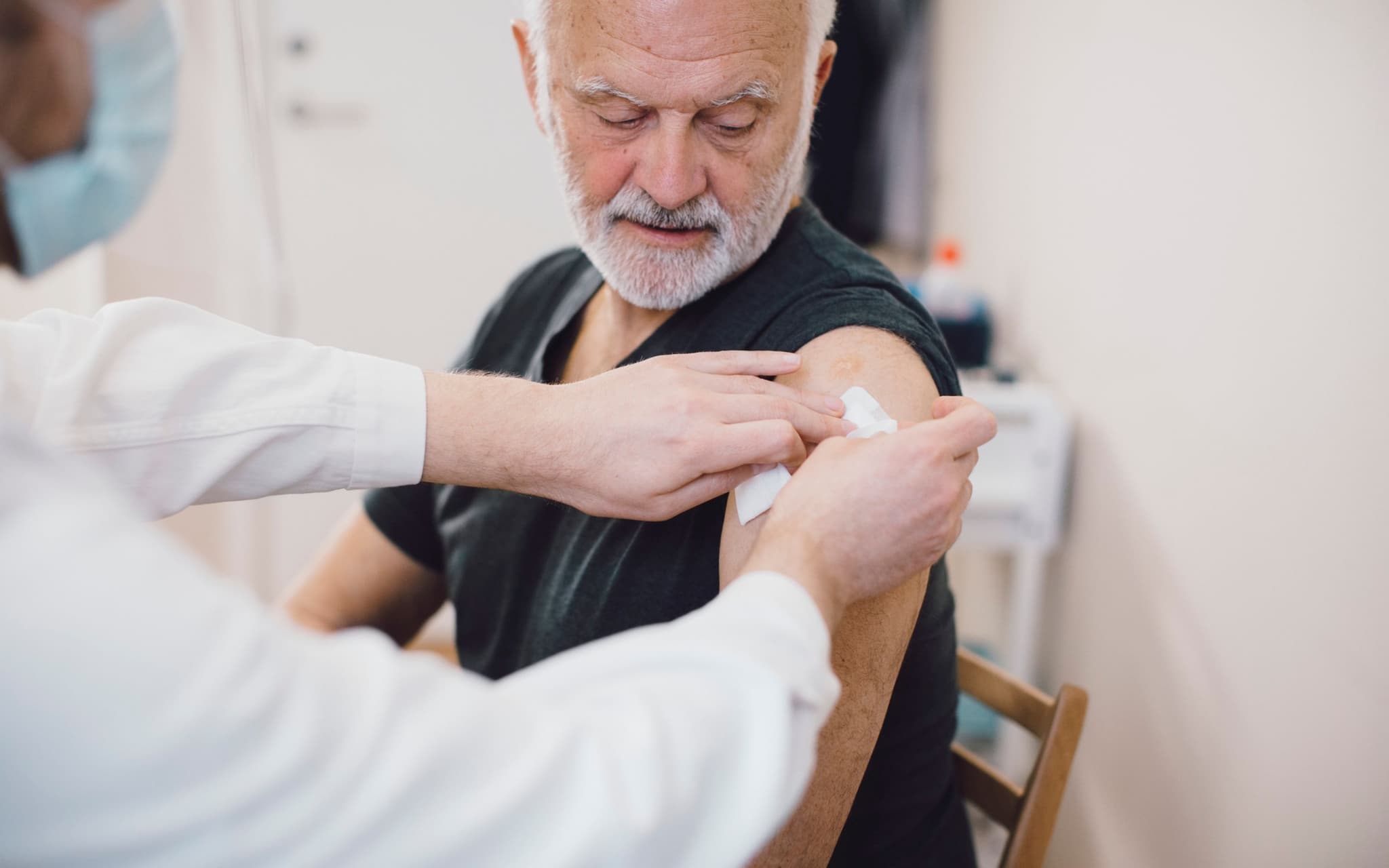 Ein älterer Mann wurde gegen Gürtelrose geimpft und bekommt ein Pflaster auf den Oberarm.