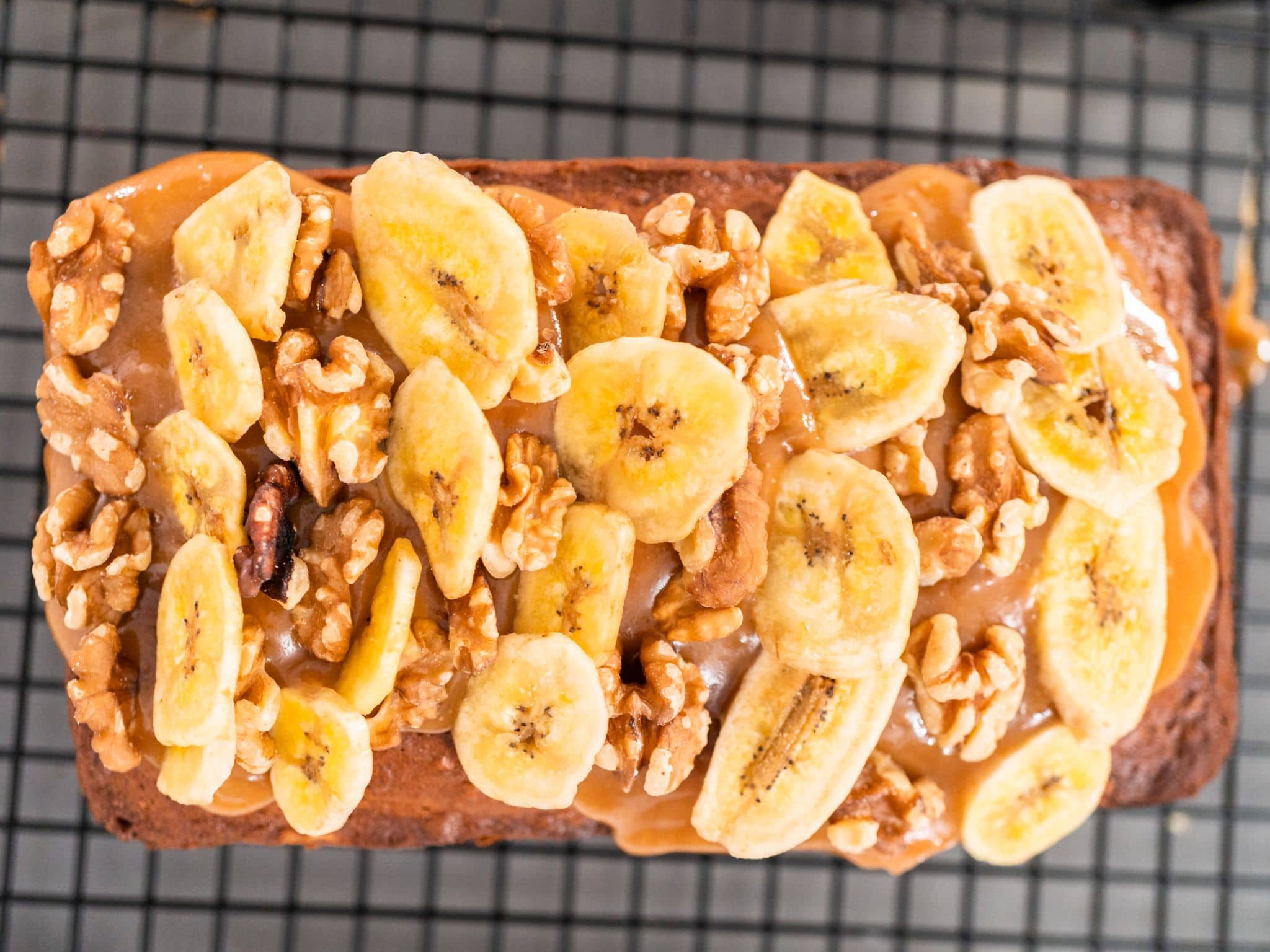 Eine gesunde, süße Frühstücksalternative: Geschnittene Bananen und Walnüsse mit Nussaufstrich auf Vollkornbrot.