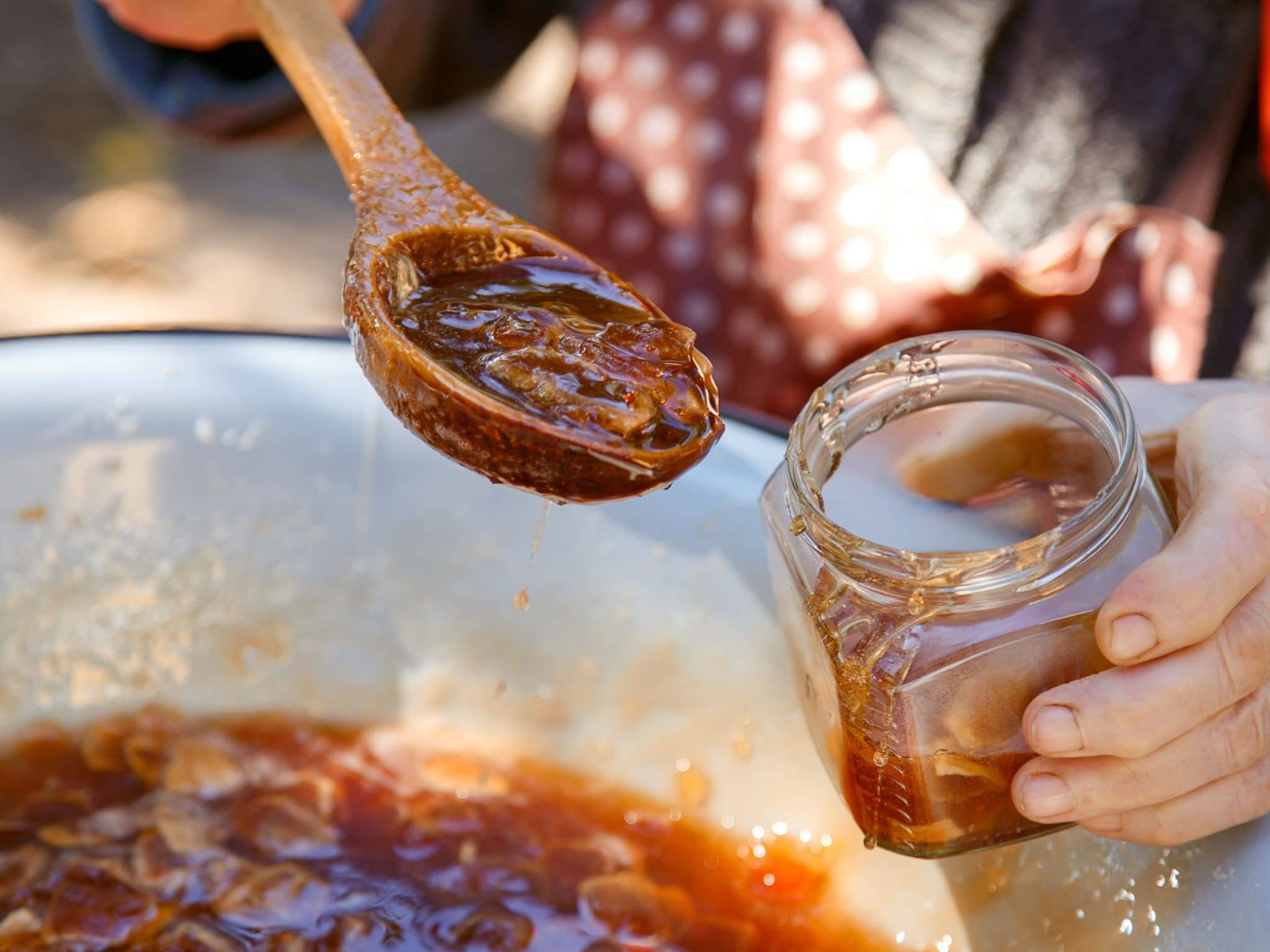 Marmelade auf dem Löffel in ein Einmachglas füllen