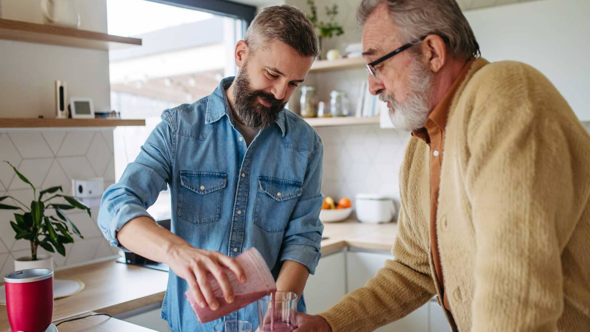 Mann füllt einen Smoothie in das Glas seines alternden Vaters