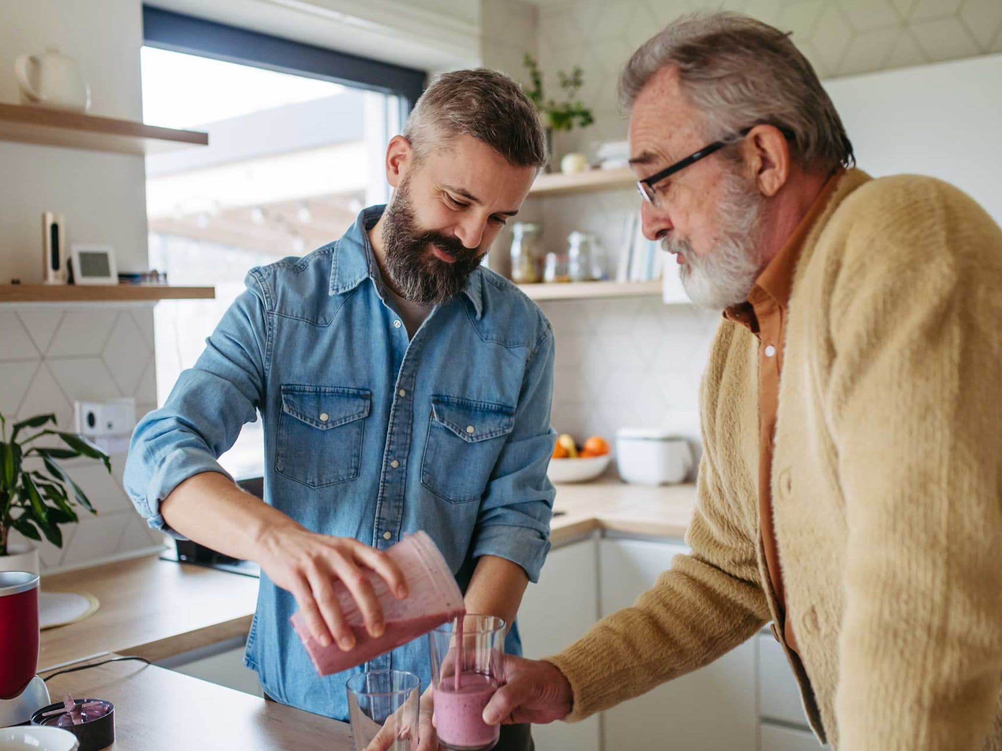 Mann füllt einen Smoothie in das Glas seines alternden Vaters