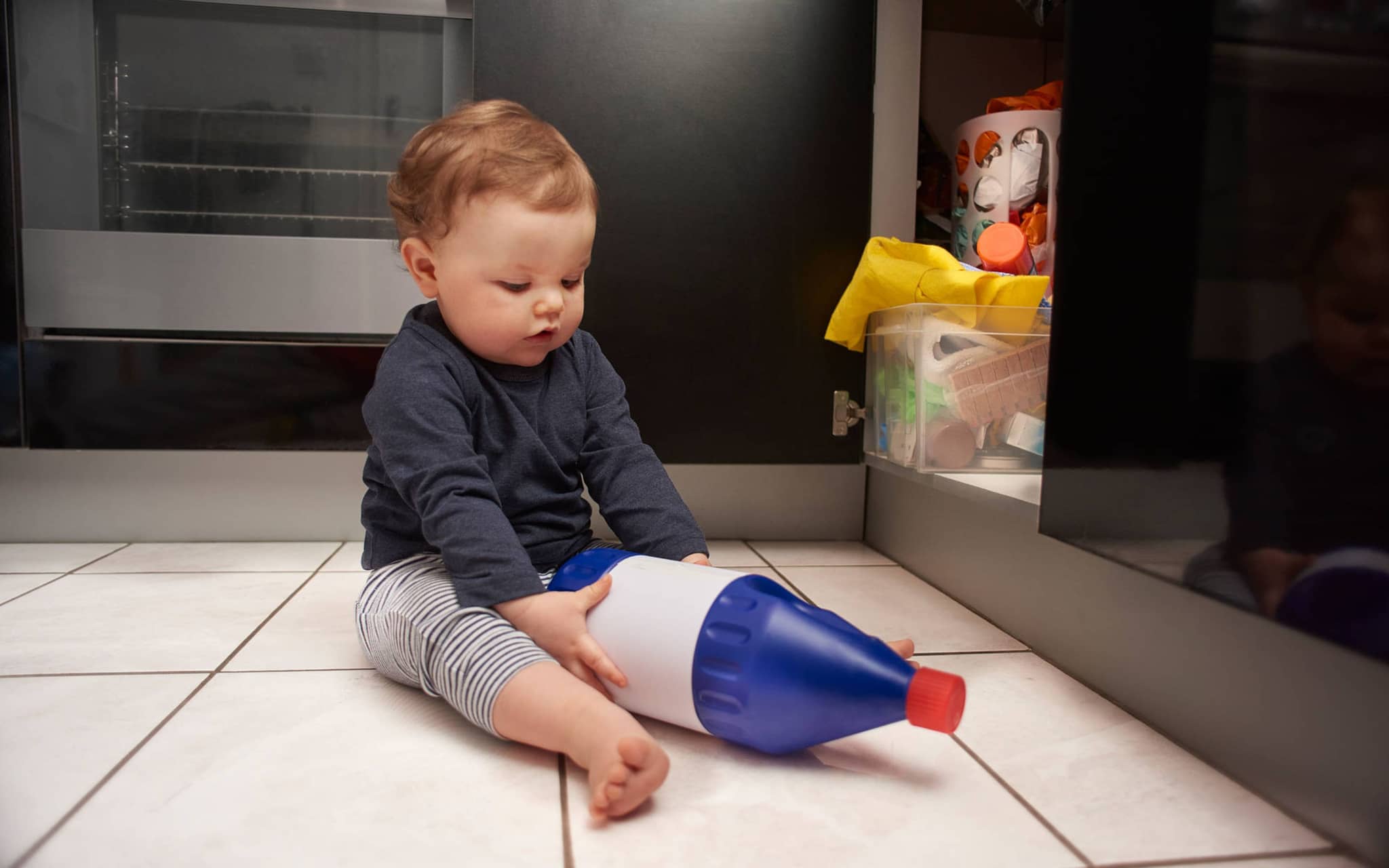 Ein Kleinkind entdeckt Reinigungsmittel. Hier besteht die Gefahr einer Vergiftung.