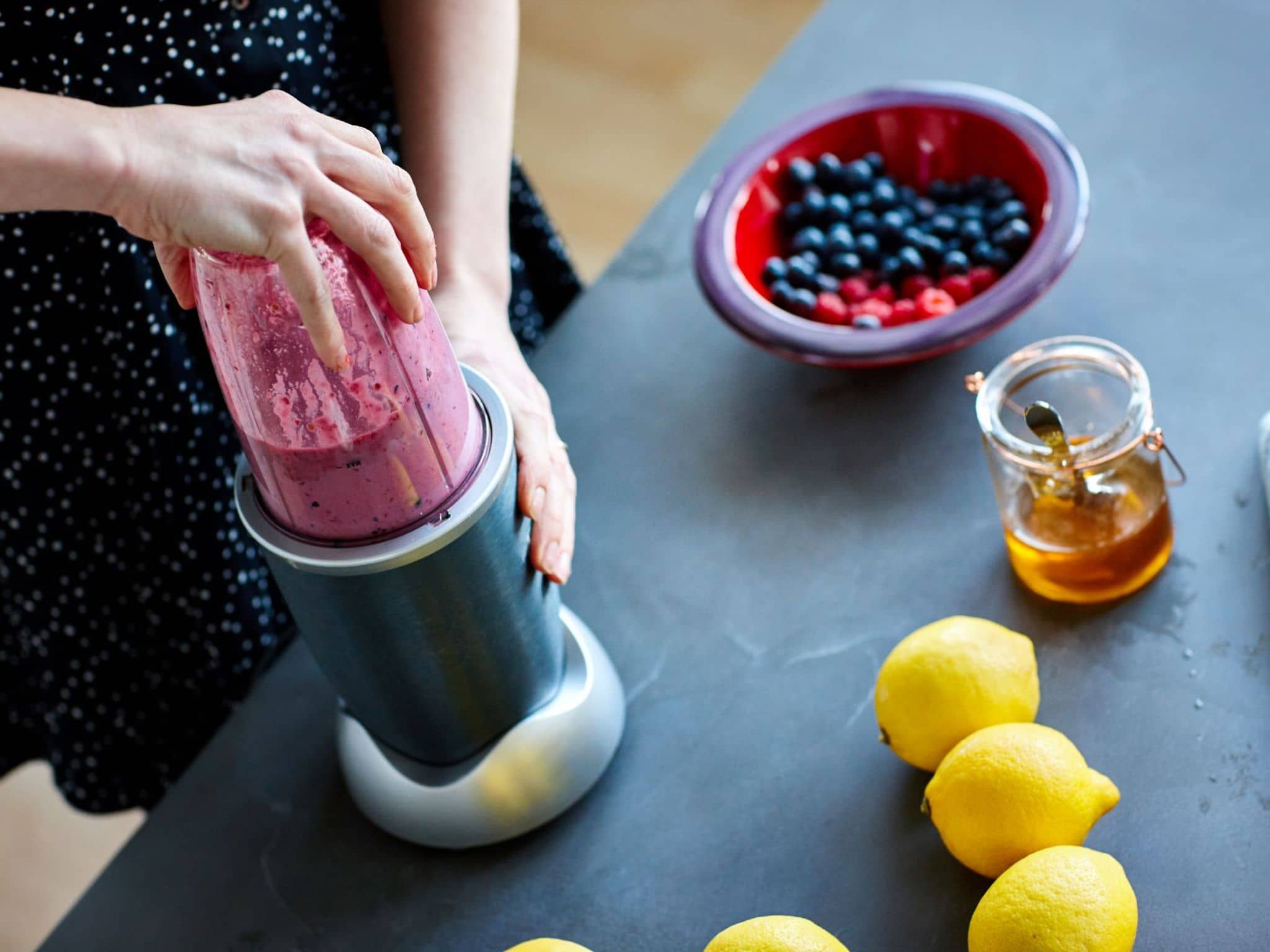 Eine Frau bereitet Beeren-Eis mit einem Standmixer zu.