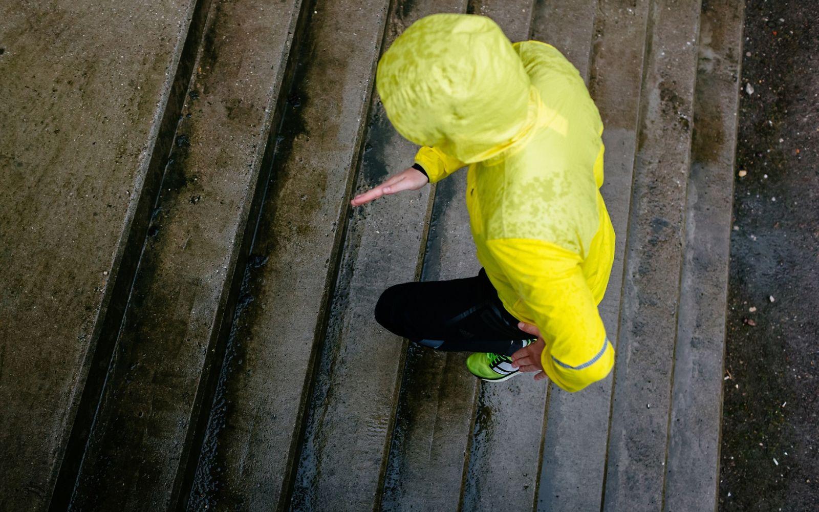 Wintermüdigkeit: Sportler in Regenkleidung läuft eine nasse Treppe hoch