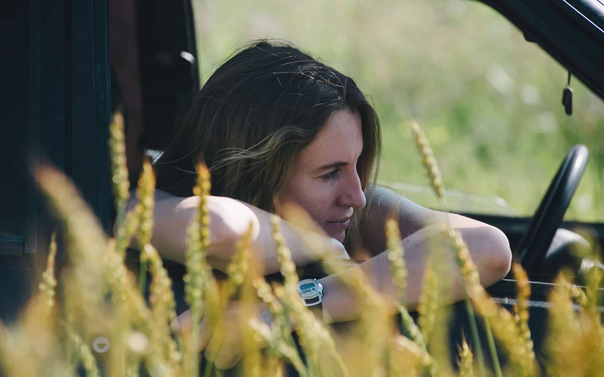 Heuschnupfen: Freu lehnt sich neben einem Kornfeld aus dem Beifahrer-Fenster eines Autos.