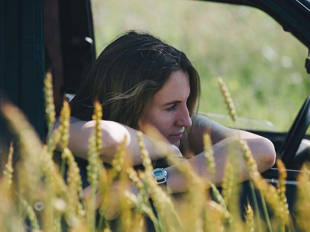 Heuschnupfen: Freu lehnt sich neben einem Kornfeld aus dem Beifahrer-Fenster eines Autos.
