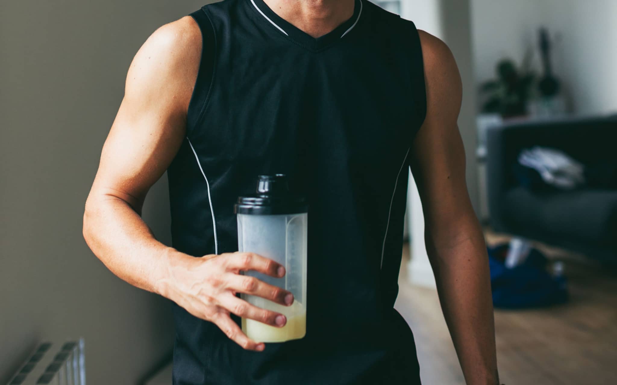 Lächelnder Mann, der einen Proteinshake nach hartem Training trinkt