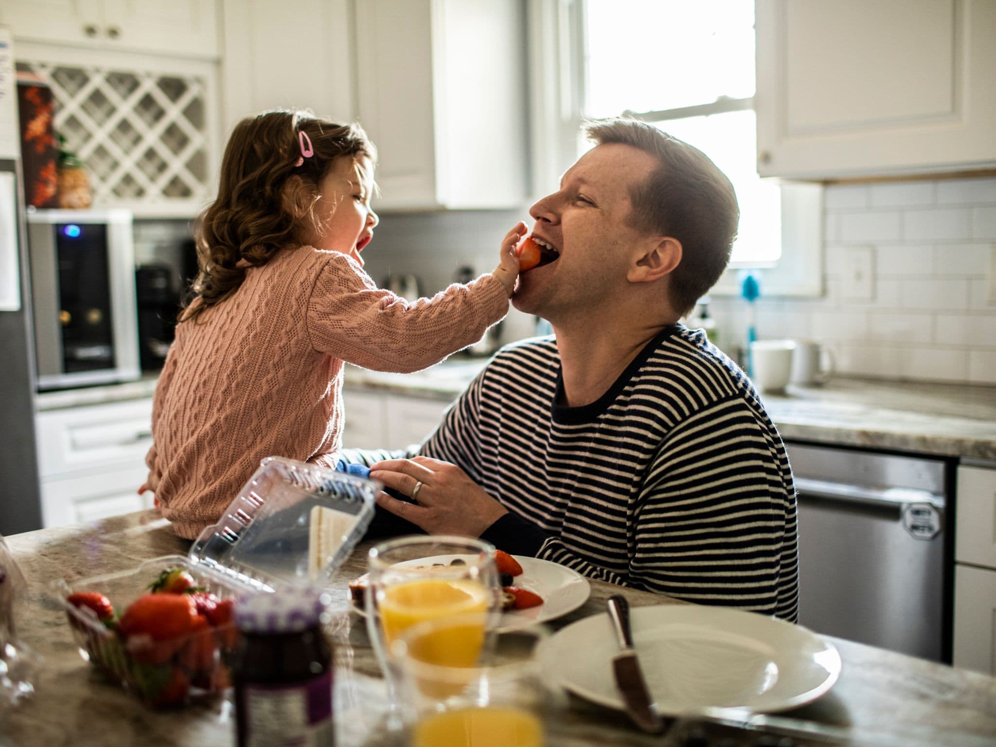 Junges Mädchen füttert ihren Vater mit gesunden Erdbeeren.