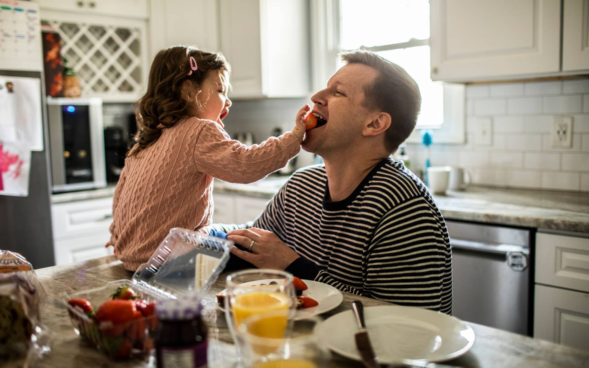 Junges Mädchen füttert ihren Vater mit gesunden Erdbeeren.