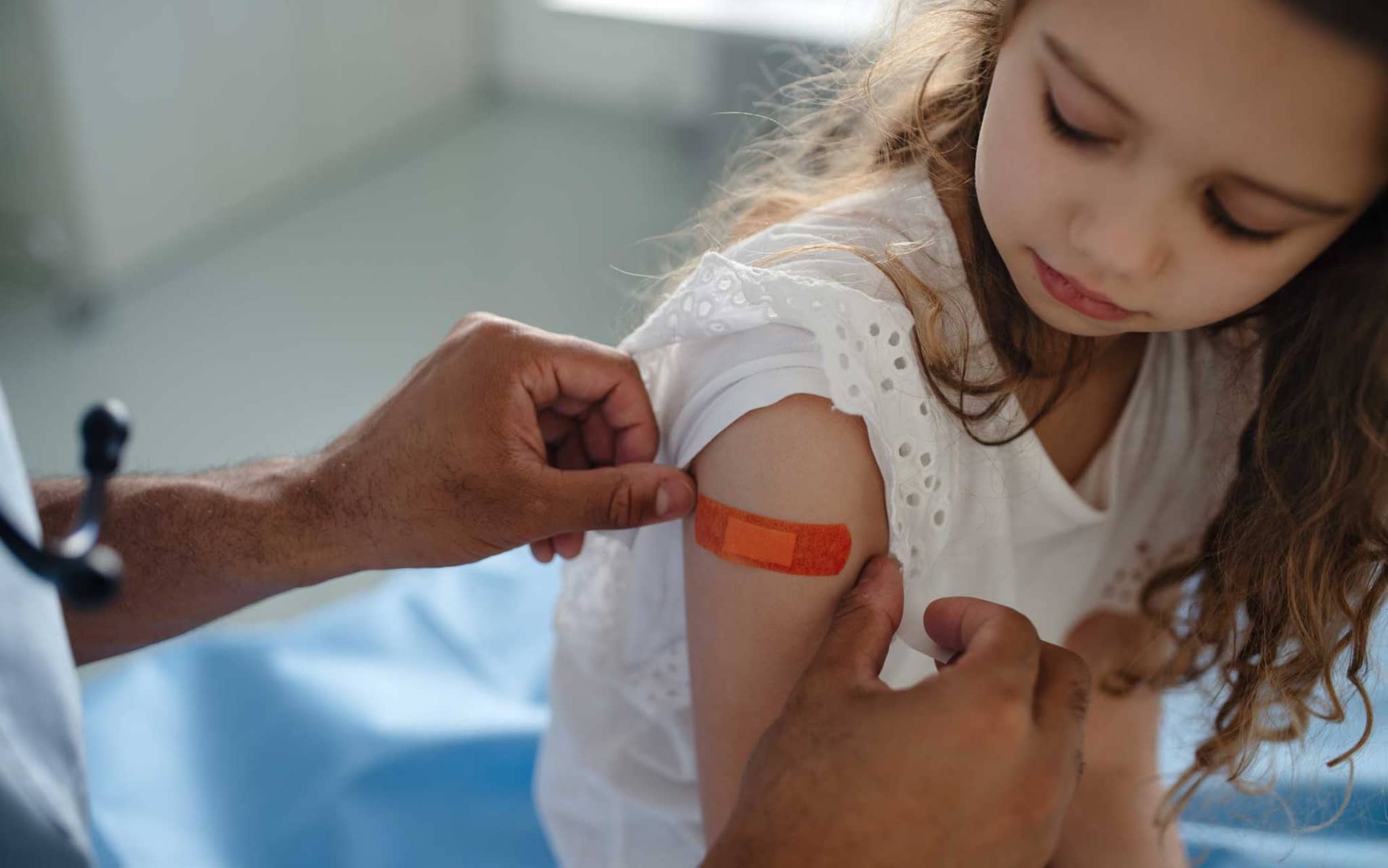 Mädchen wird Pflaster auf den Oberarm geklebt
