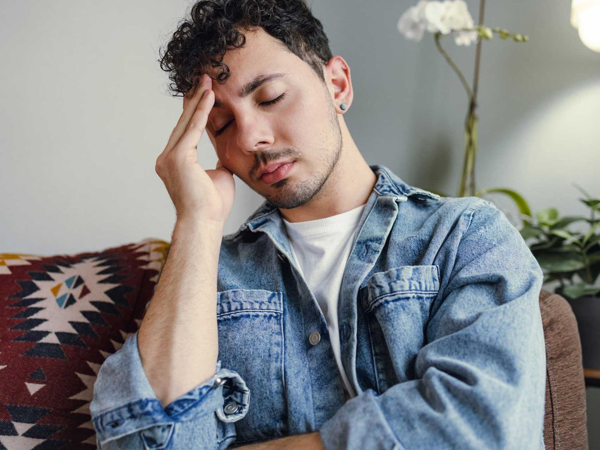 Junger Mann hält sich den schmerzenden Kopf