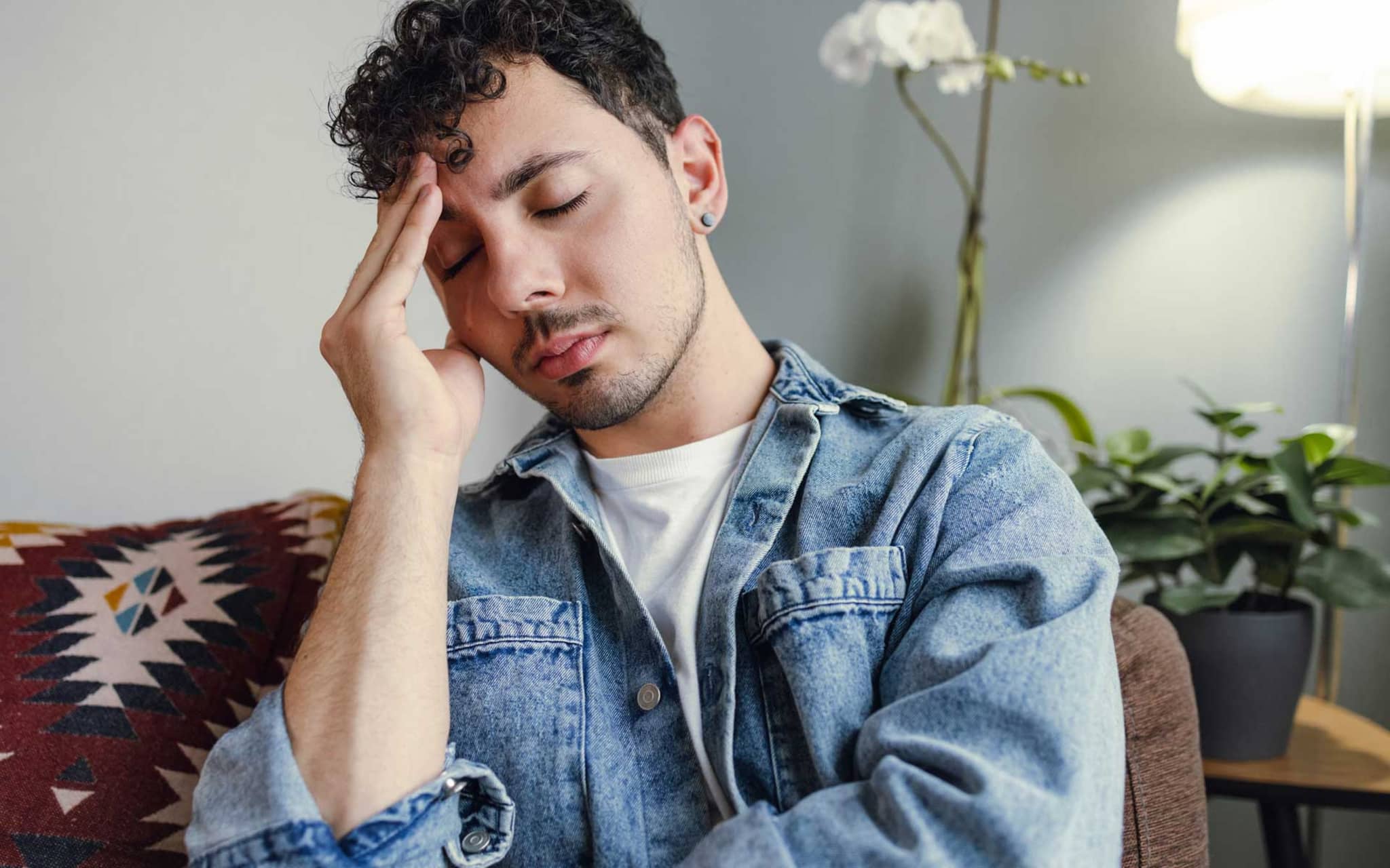 Junger Mann hält sich den schmerzenden Kopf