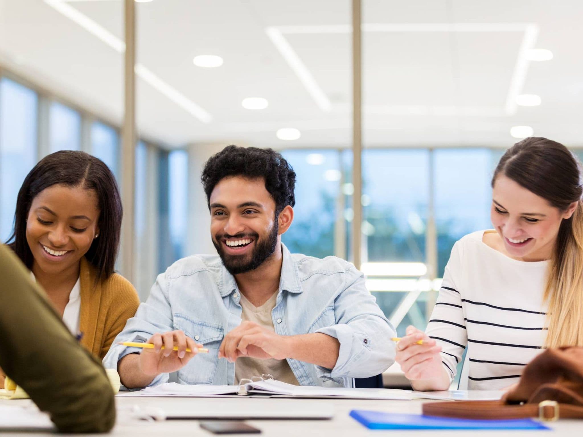 Gruppe Studierender sitzen an einem Tisch und lachen.