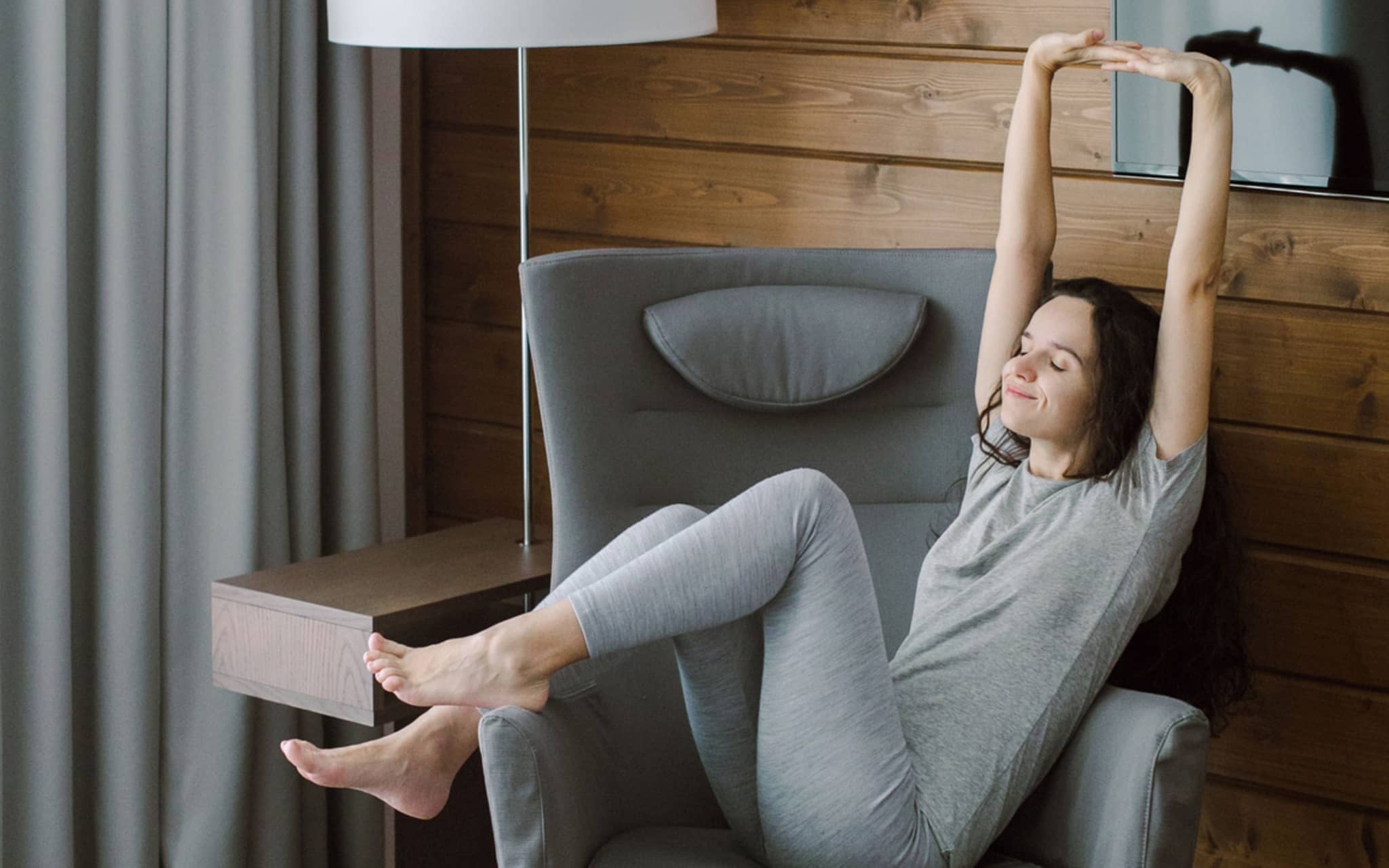 Trainingspause: Frau streckt sich in einem Sessel