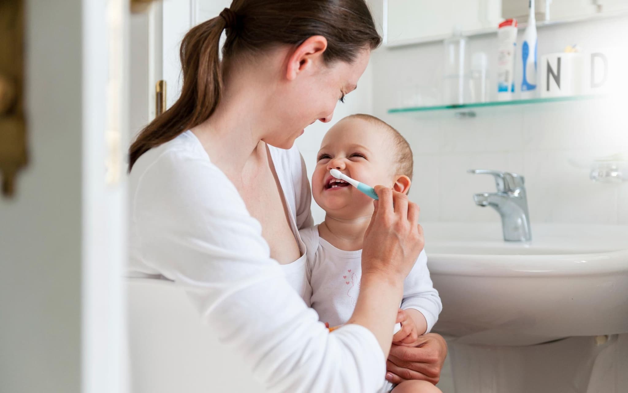 Zahnpflege bei Babys: Eine Mutter putzt die Zähne ihres Kleinkinds.