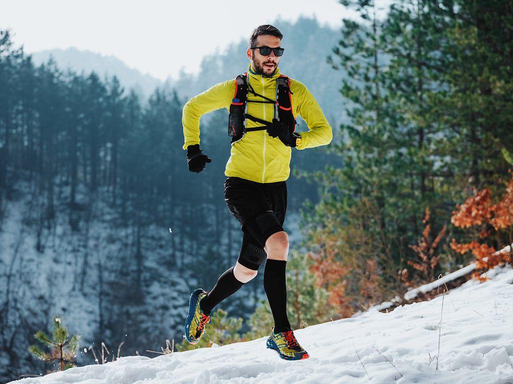 Sport im Winter: Ein Läufer auf einem verschneiten Trail in den Bergen