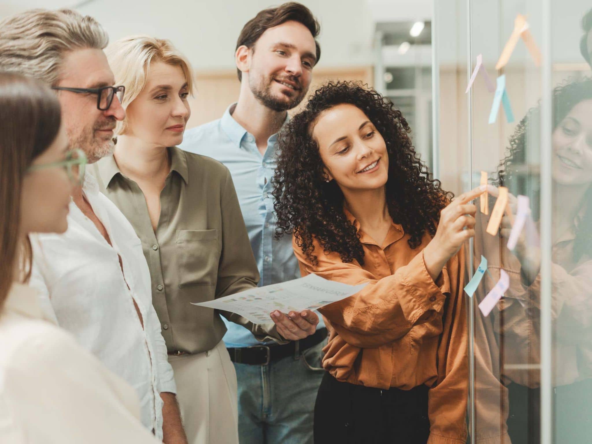 Gesundheitsreport 2025: Gruppe von jungen Leuten klebt bei einem Workshop im Büro Post-its an eine Glaswand.