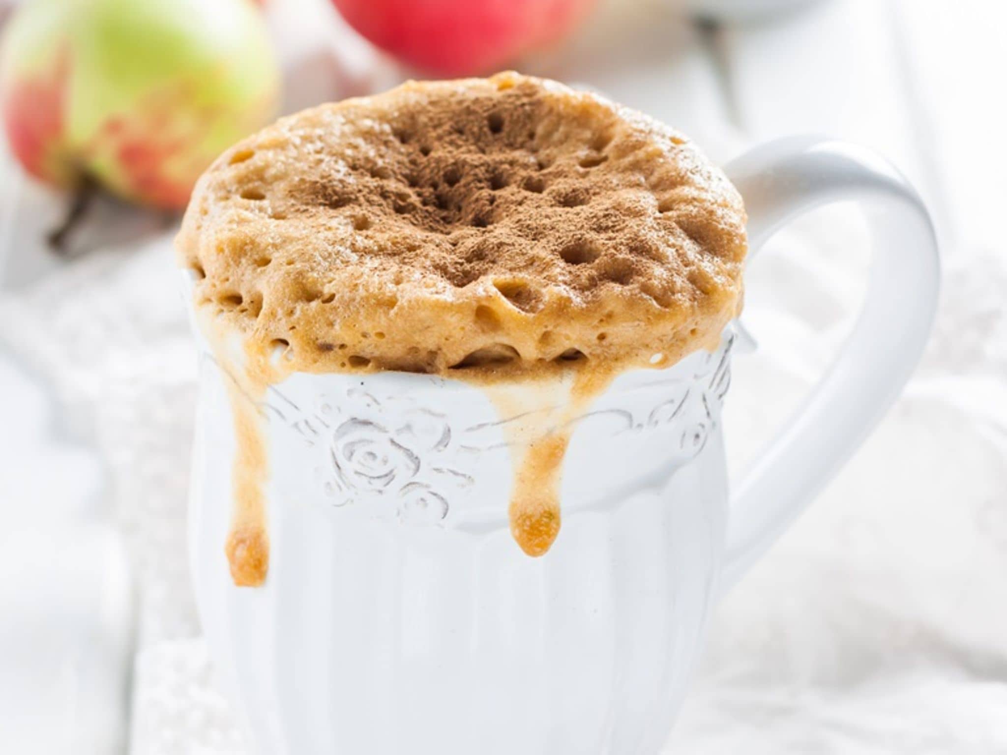 Apfel-Tassenkuchen: Weiße Tasse mit einem fast überlaufenden Tassenkuchen