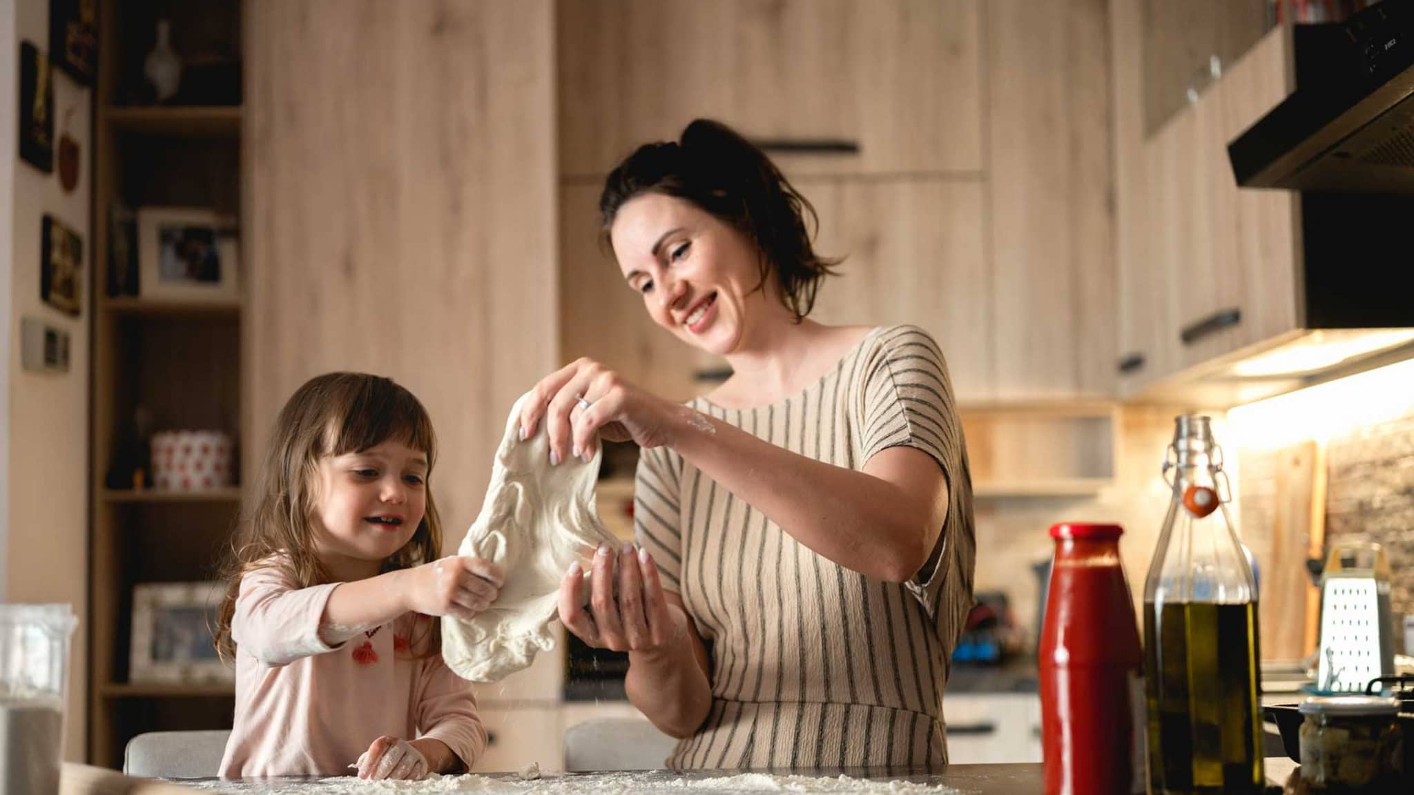 Mutter und Tochter kneten Pizzateig