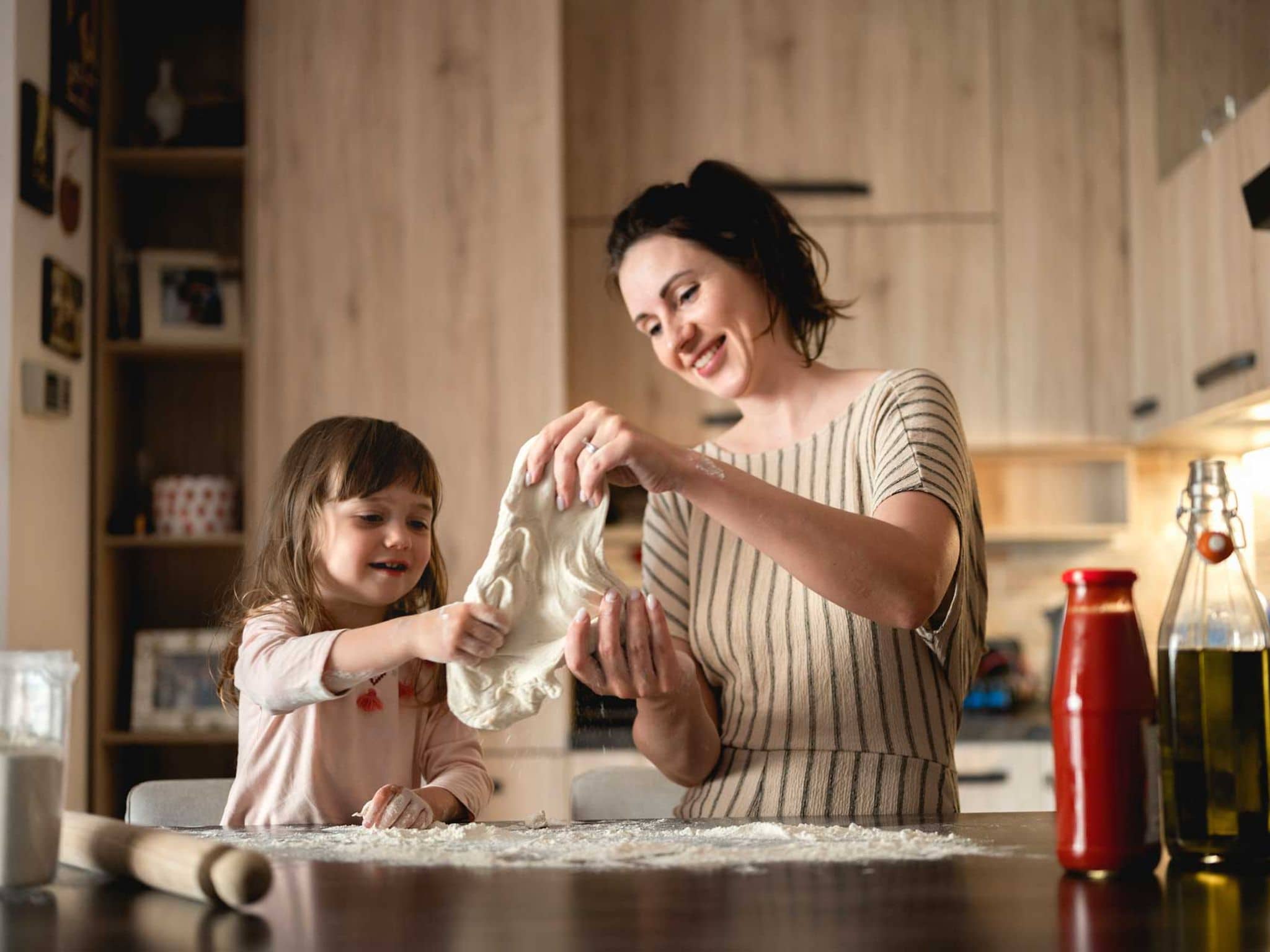 Mutter und Tochter kneten Pizzateig