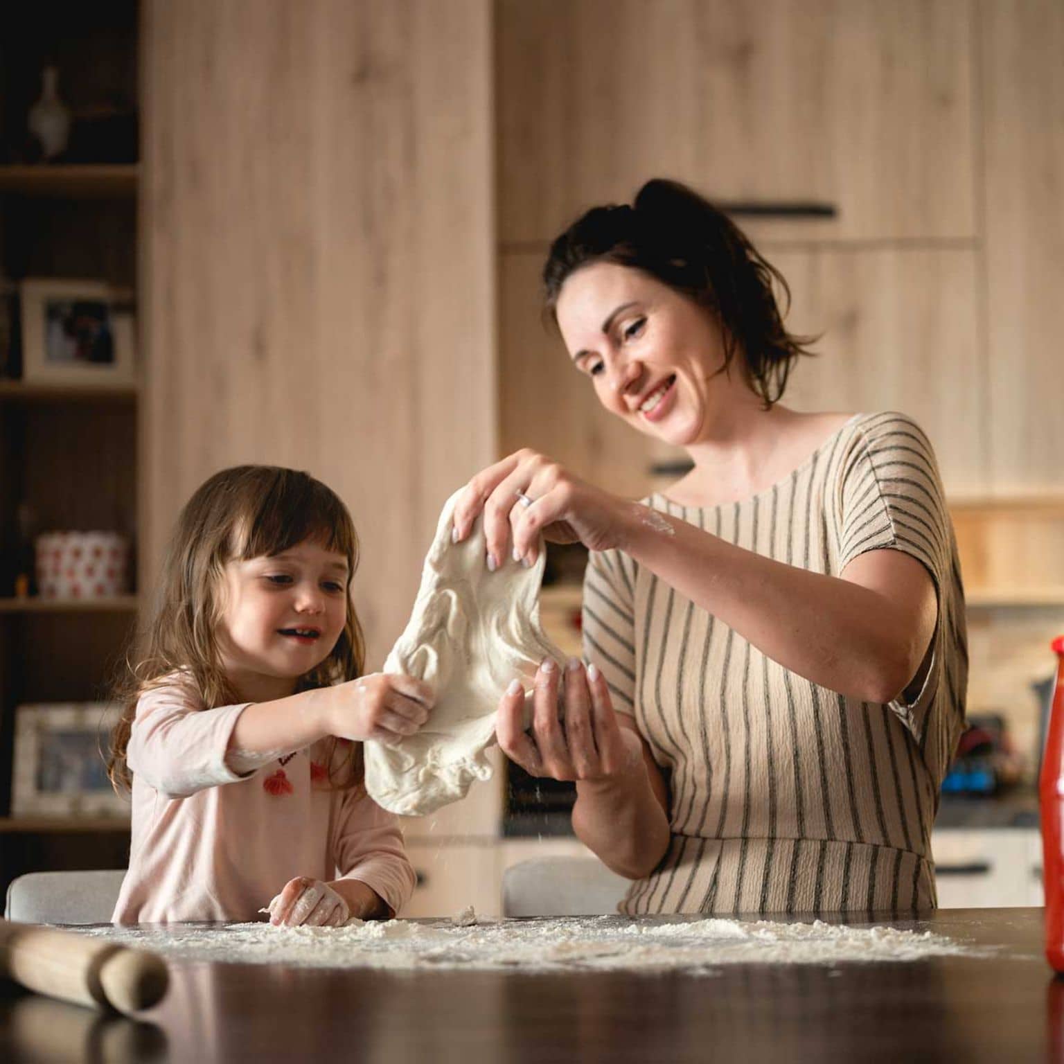 Mutter und Tochter kneten Pizzateig