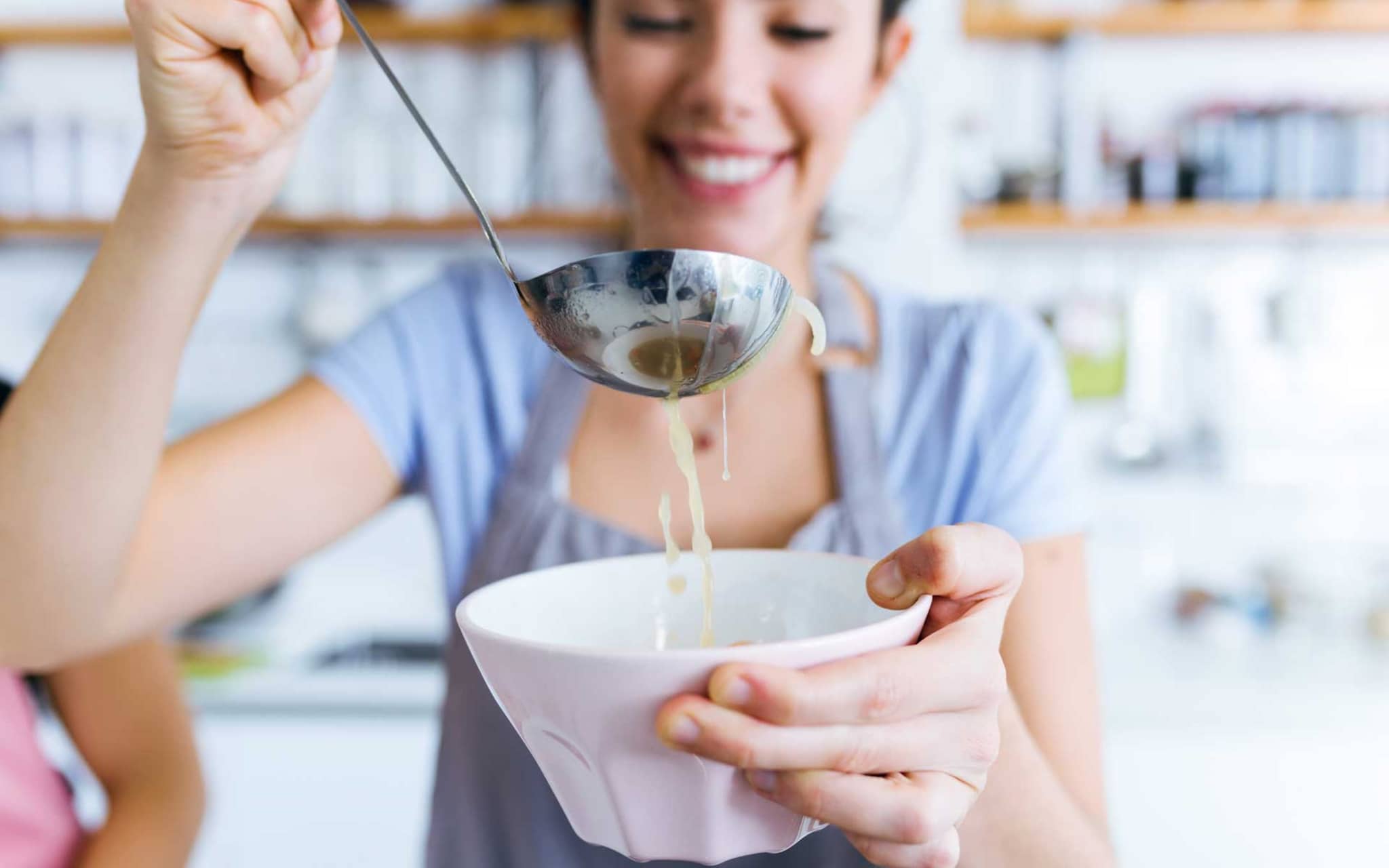 Frau füllt Suppe in eine Schüssel
