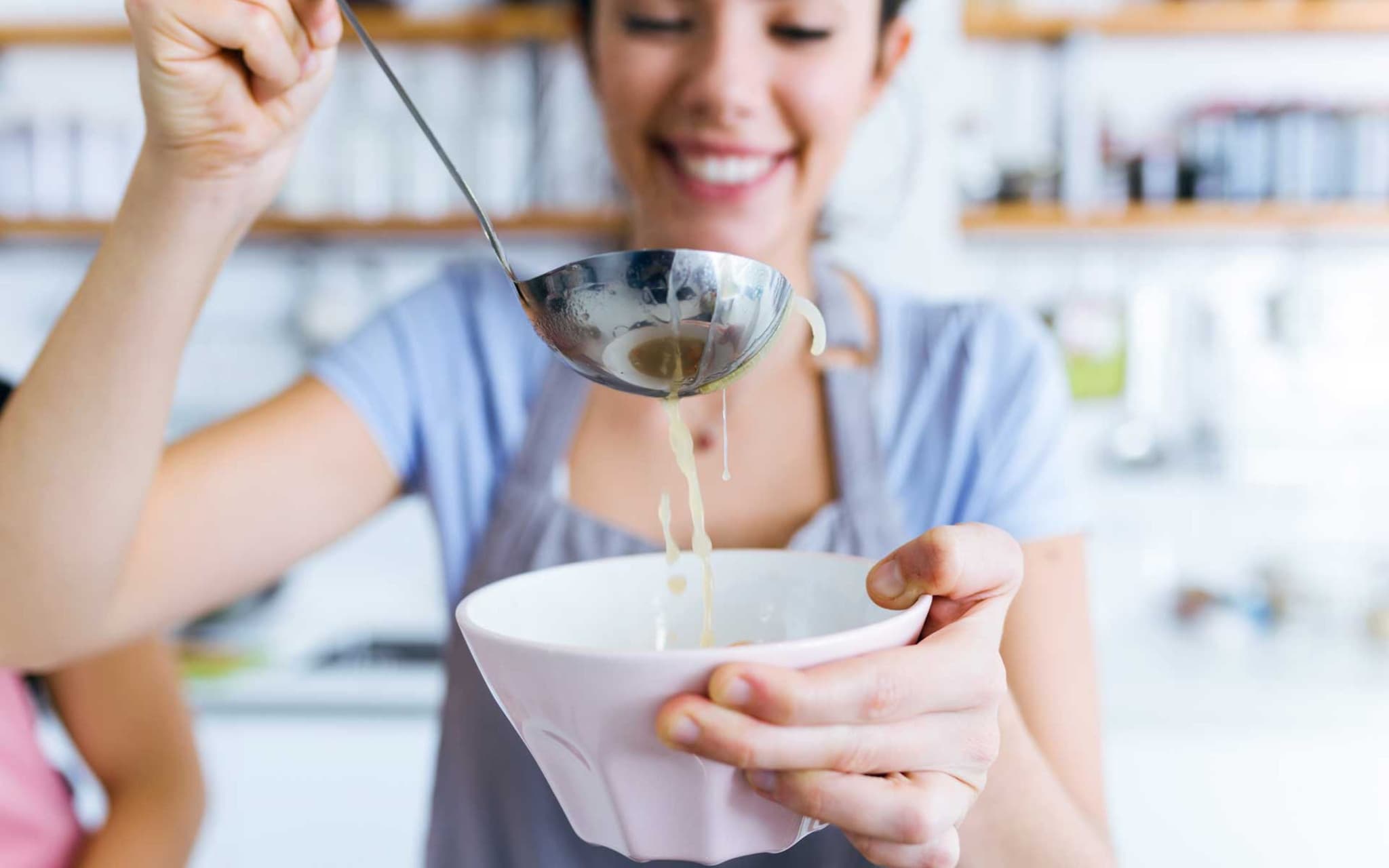 Frau füllt Suppe in eine Schüssel