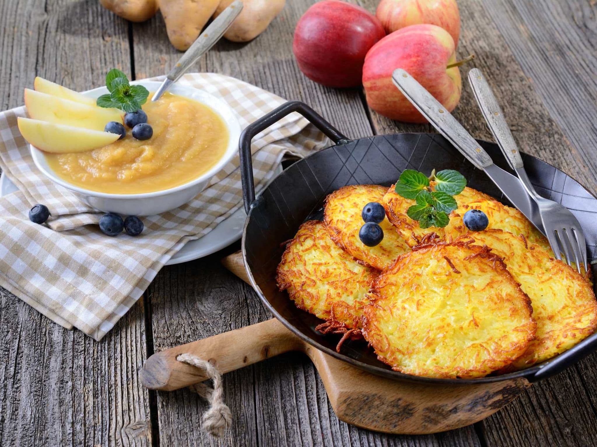 Kartoffelpuffer im Pfännchen, daneben eine Schale mit Apfelmus