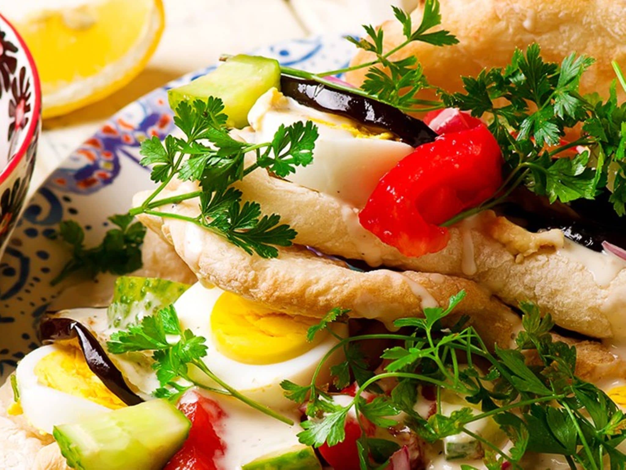 Ein Teller mit Sabich – gefüllt mit gekochtem Ei, Paprika, Zwiebeln, Petersilie und Aubergine.