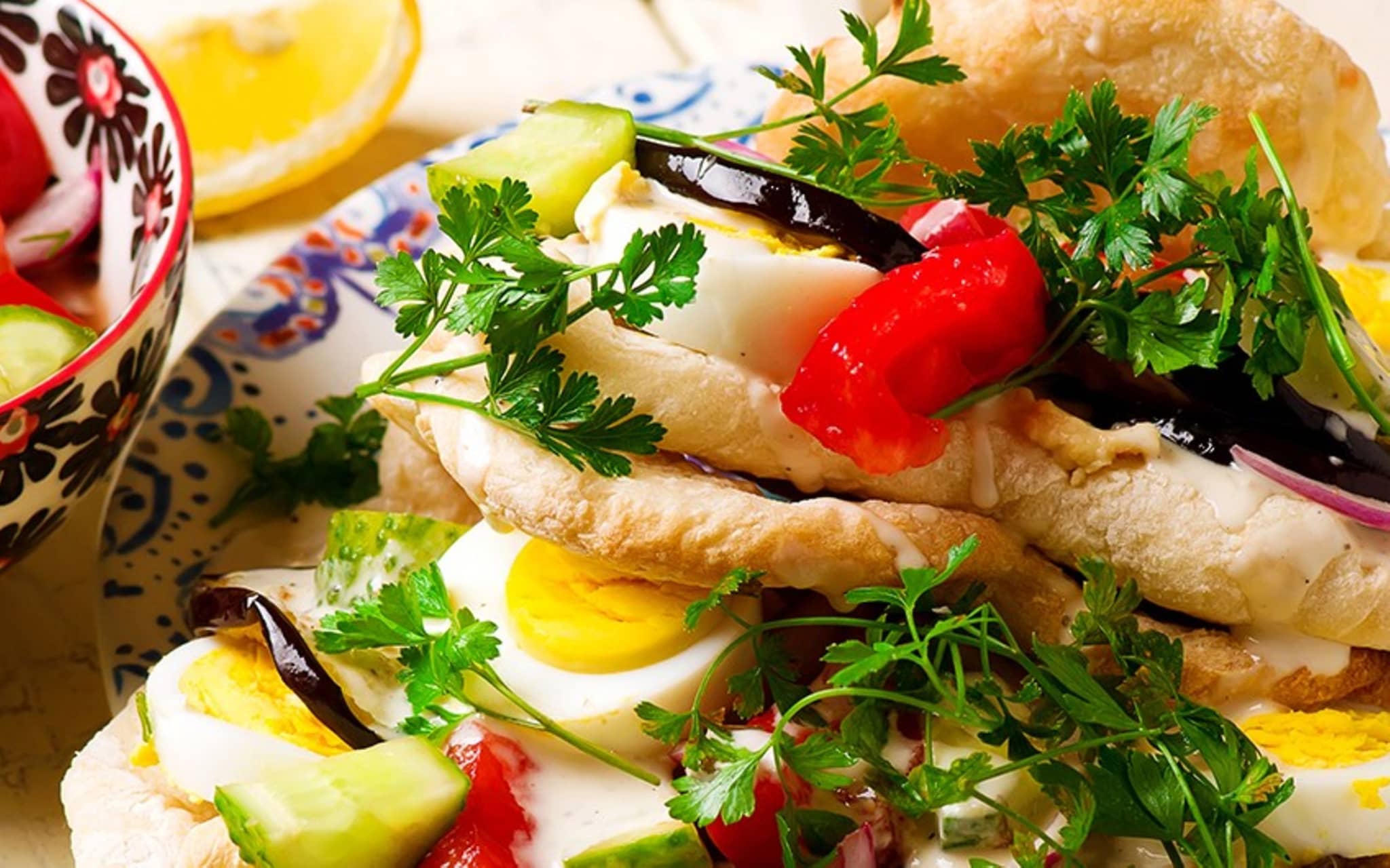 Ein Teller mit Sabich – gefüllt mit gekochtem Ei, Paprika, Zwiebeln, Petersilie und Aubergine.