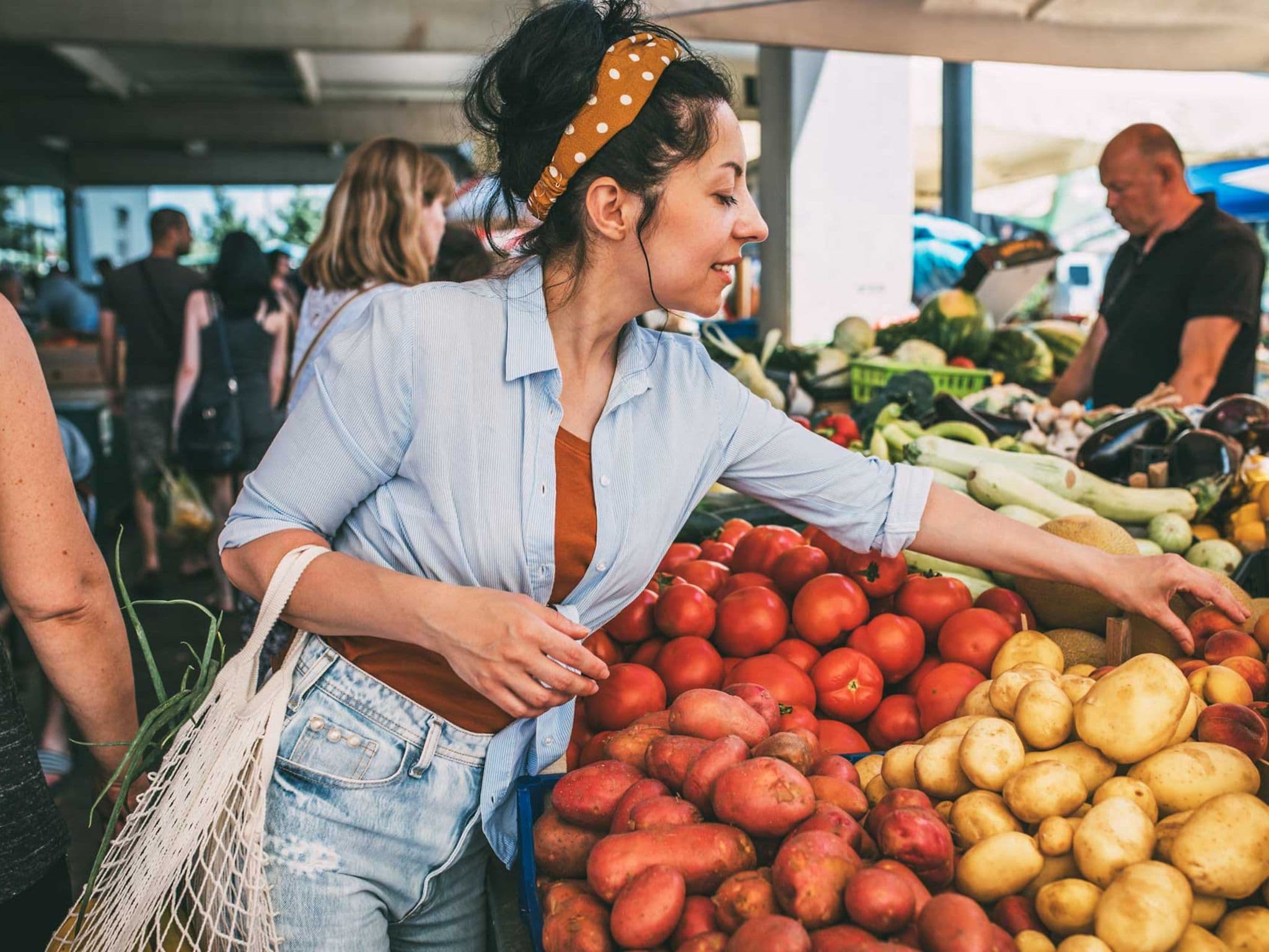 Frau greift zu Obst am Marktstand