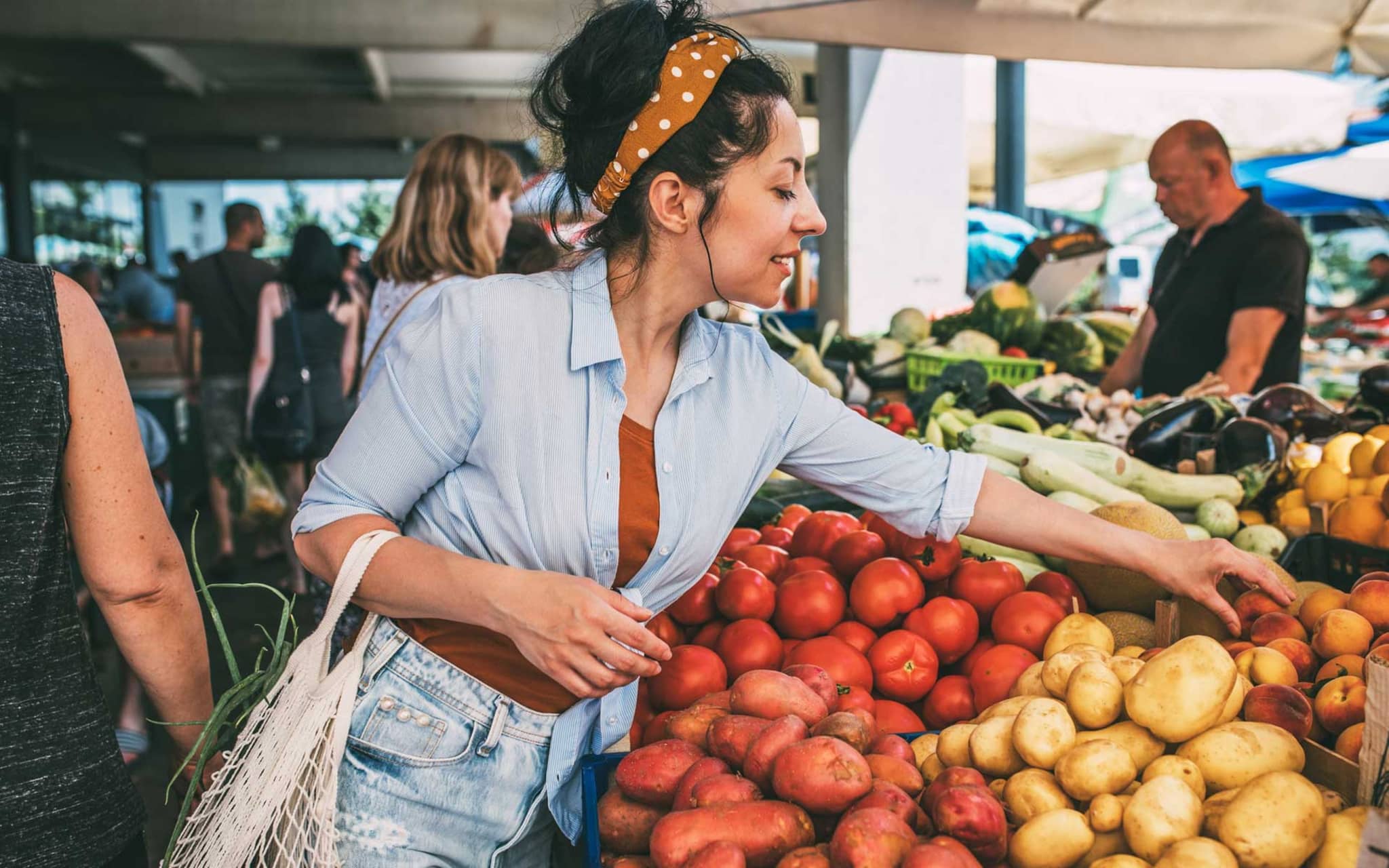 Frau greift zu Obst am Marktstand