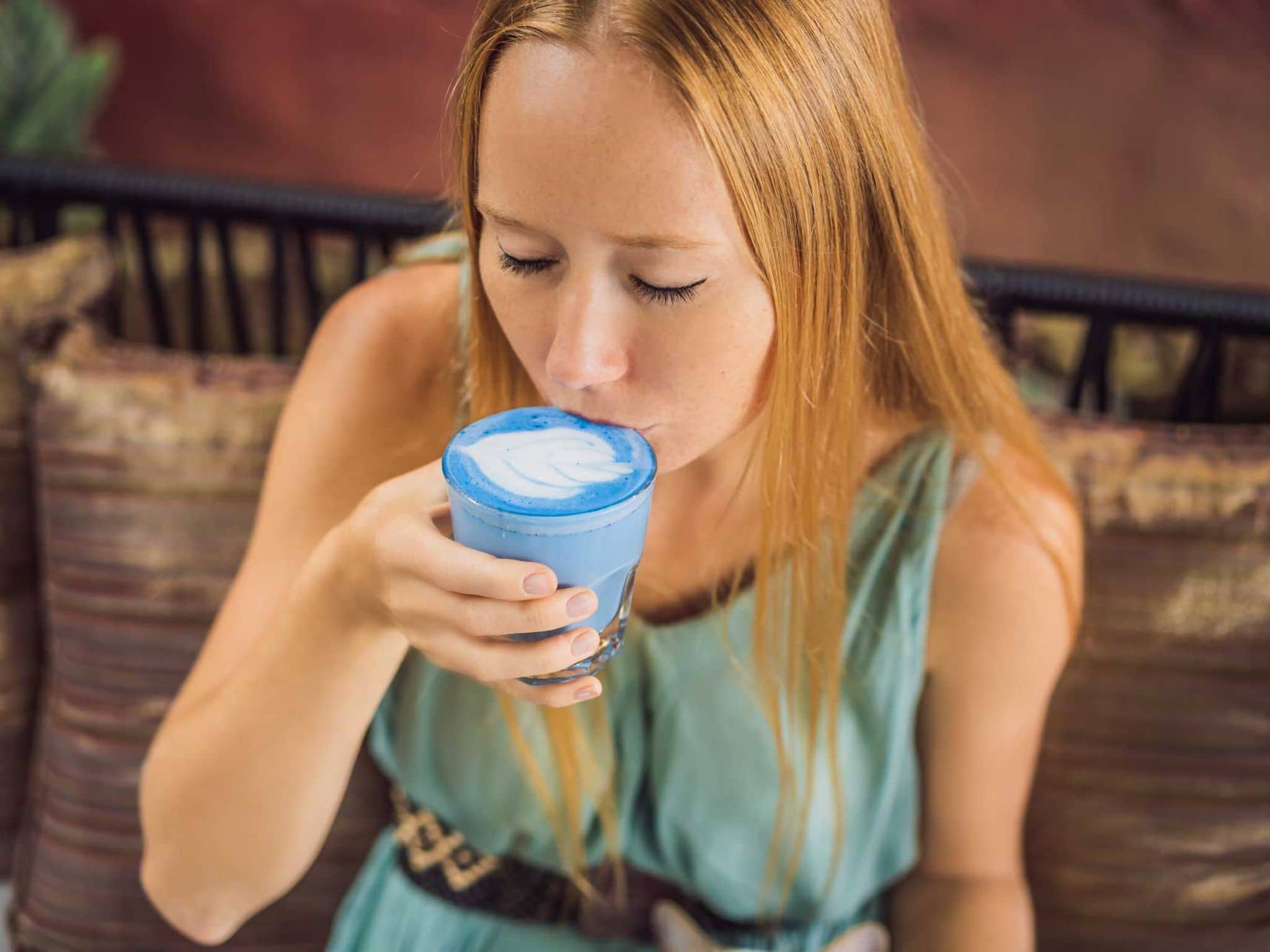 Junge Frau trinkt einen blauen Macchiato