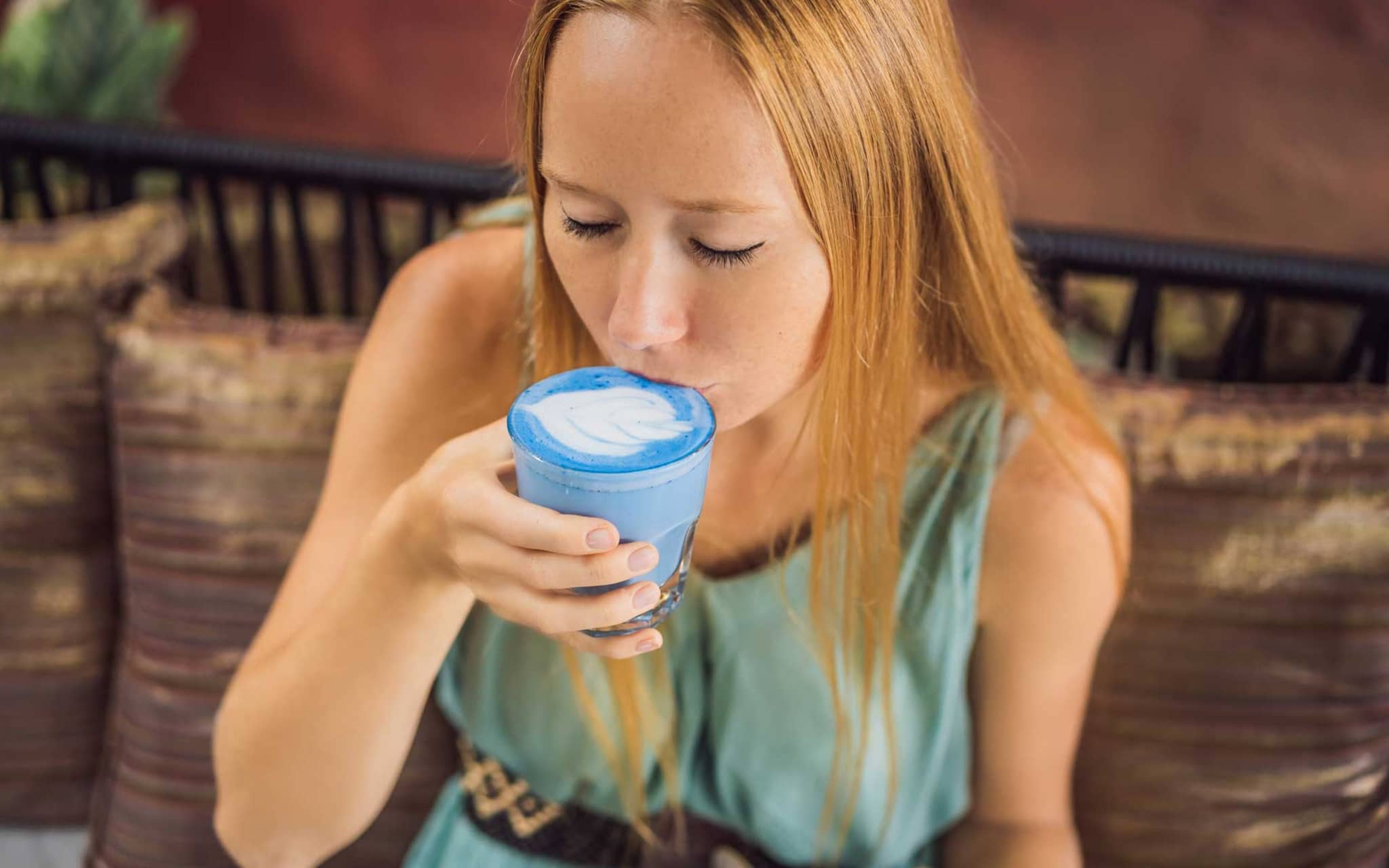 Junge Frau trinkt einen blauen Macchiato