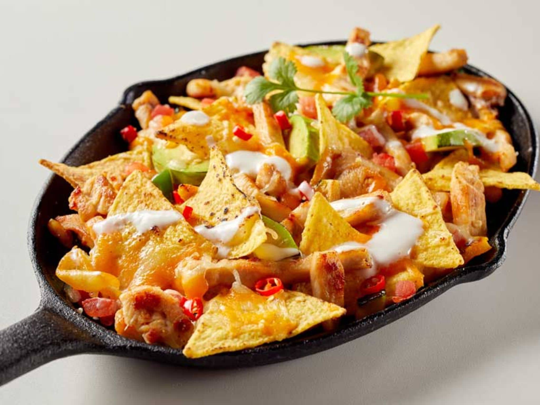 Pfännchen mit überbackenen Nachos und Chilis