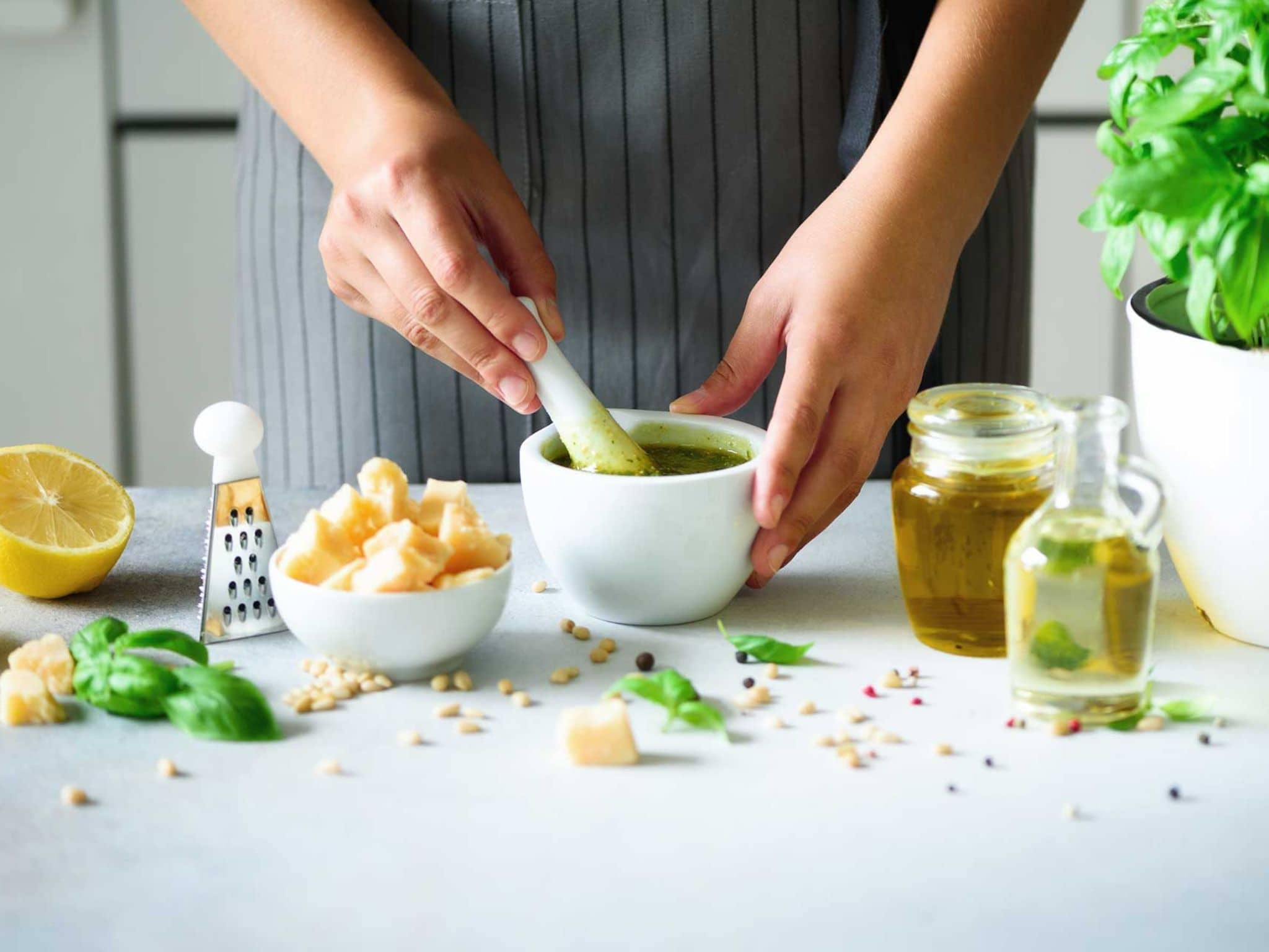 Frau bereitet ein Basilikum-Pesto im Mörser zu