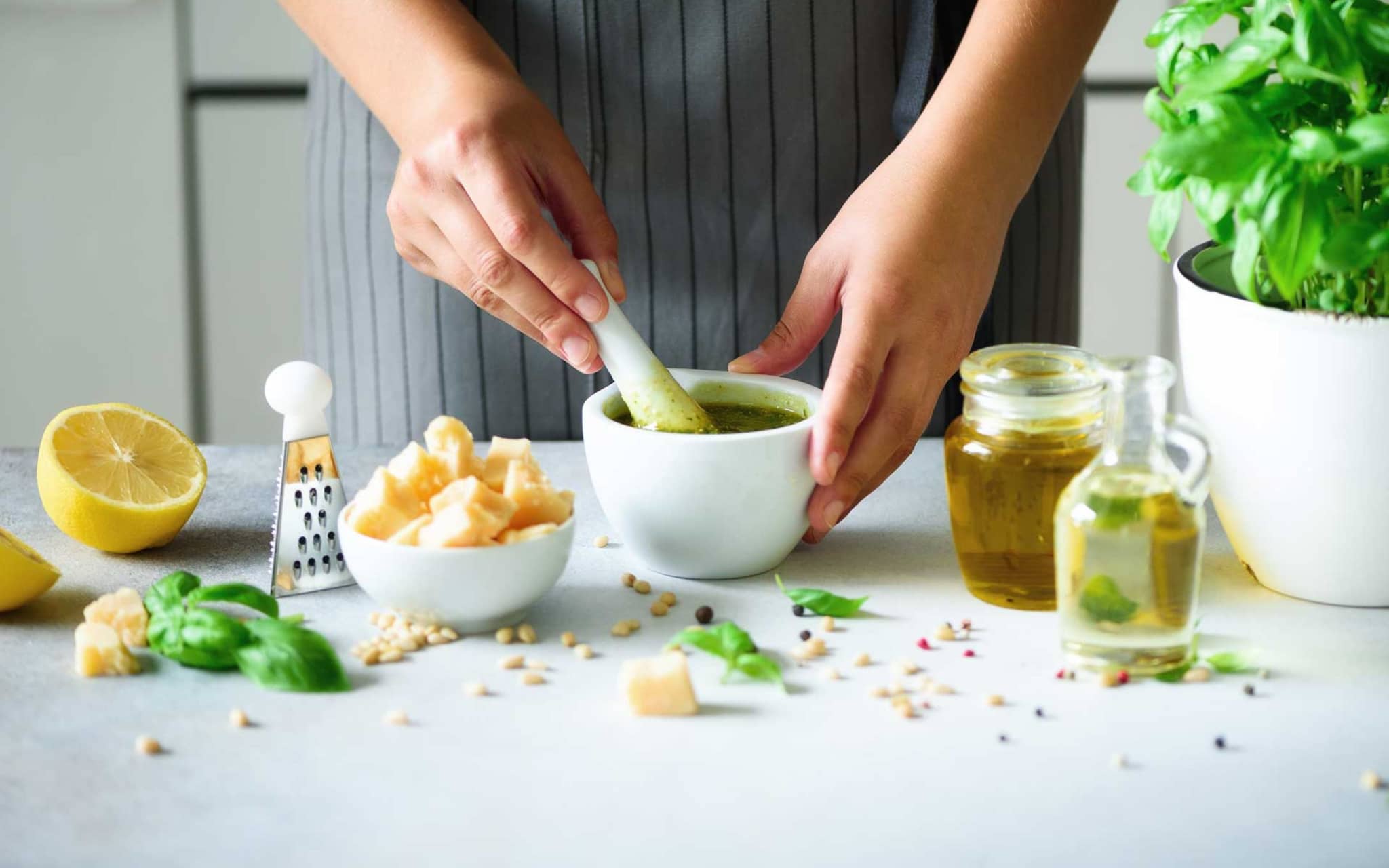 Frau bereitet ein Basilikum-Pesto im Mörser zu