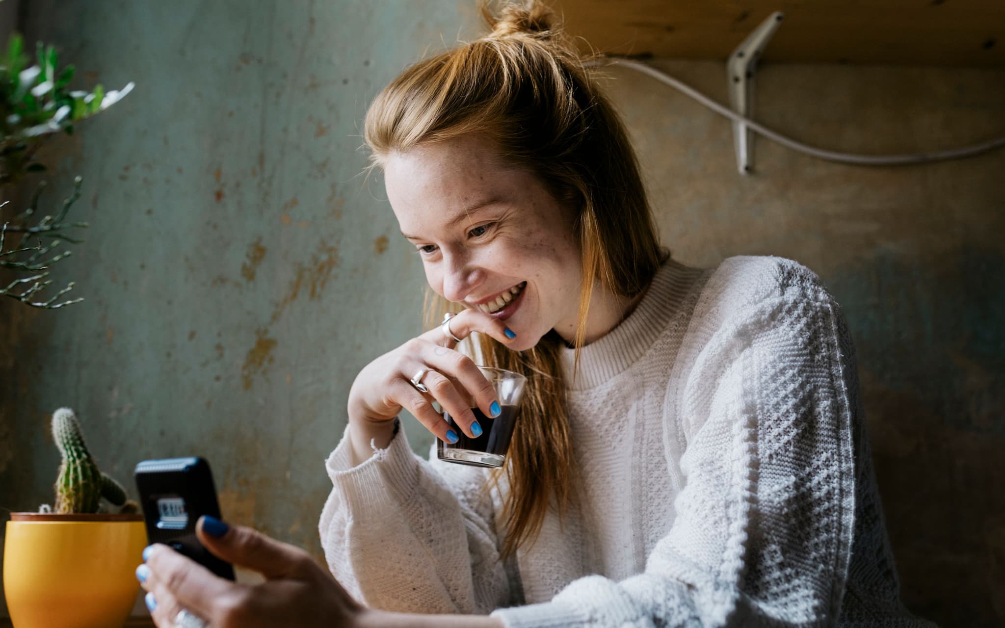 Erstes Date: Eine junge Frau liest eine Nachricht auf ihrem Smartphone und lächelt