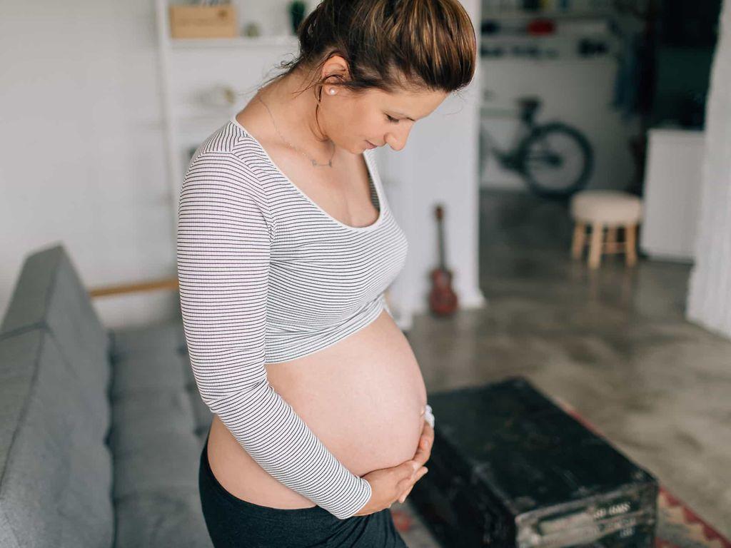 Schwangerschaftsdiabetes: Junge Schwangere betrachtet ihren nackten Bauch.