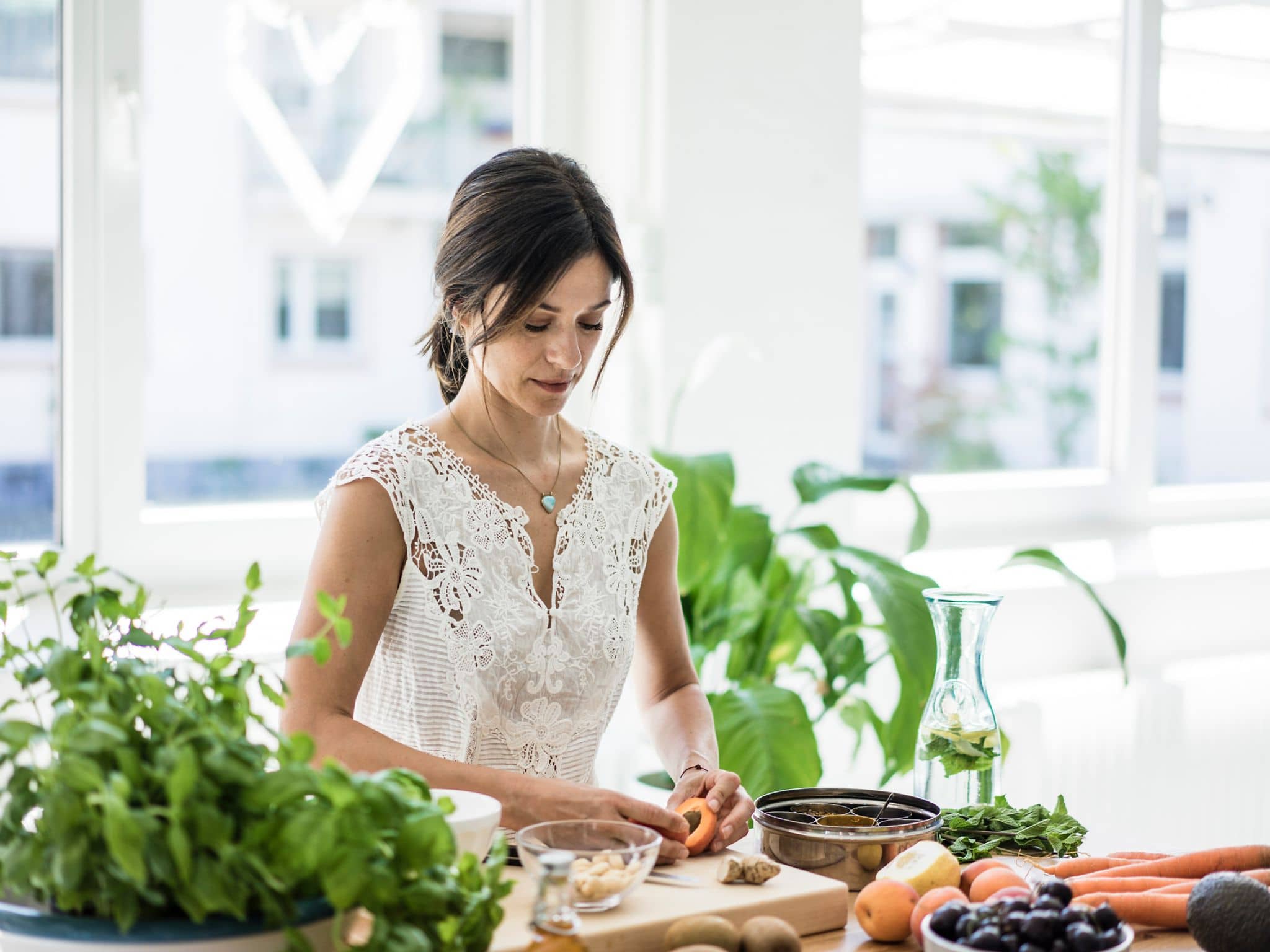 Symbolbild Ayurvedische Ernährung: Frau steht in Küche bereitet Mahlzeit vor.