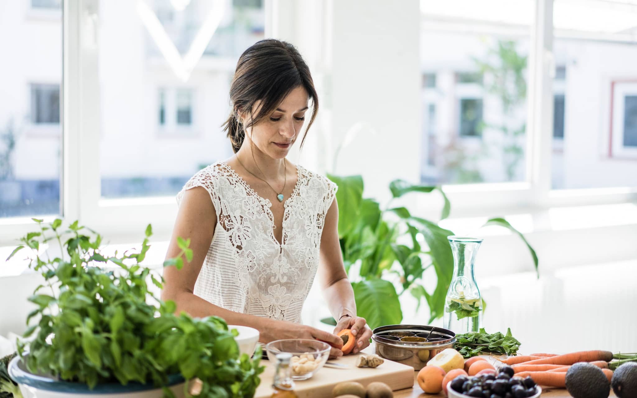 Symbolbild Ayurvedische Ernährung: Frau steht in Küche bereitet Mahlzeit vor.
