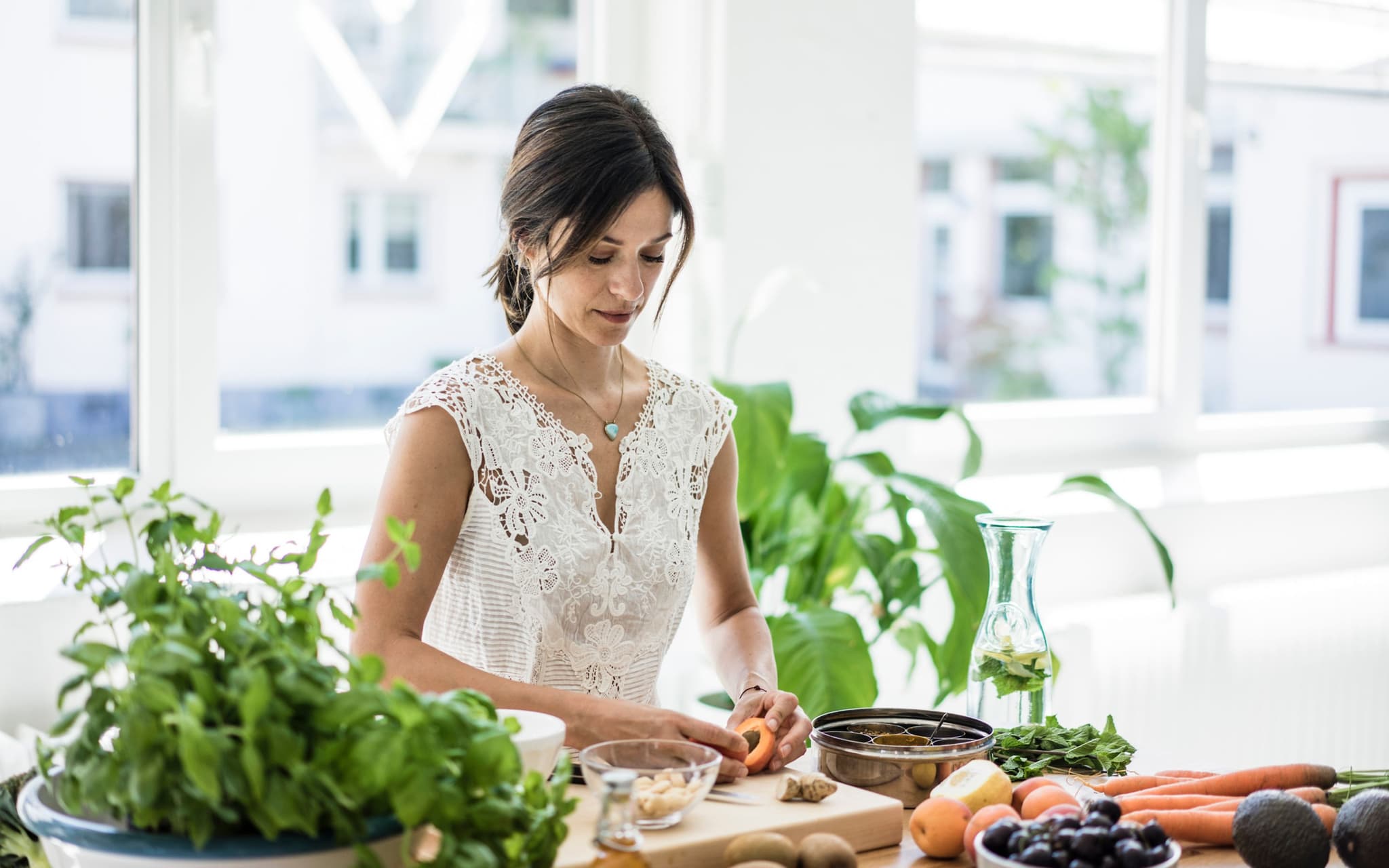 Symbolbild Ayurvedische Ernährung: Frau steht in Küche bereitet Mahlzeit vor.
