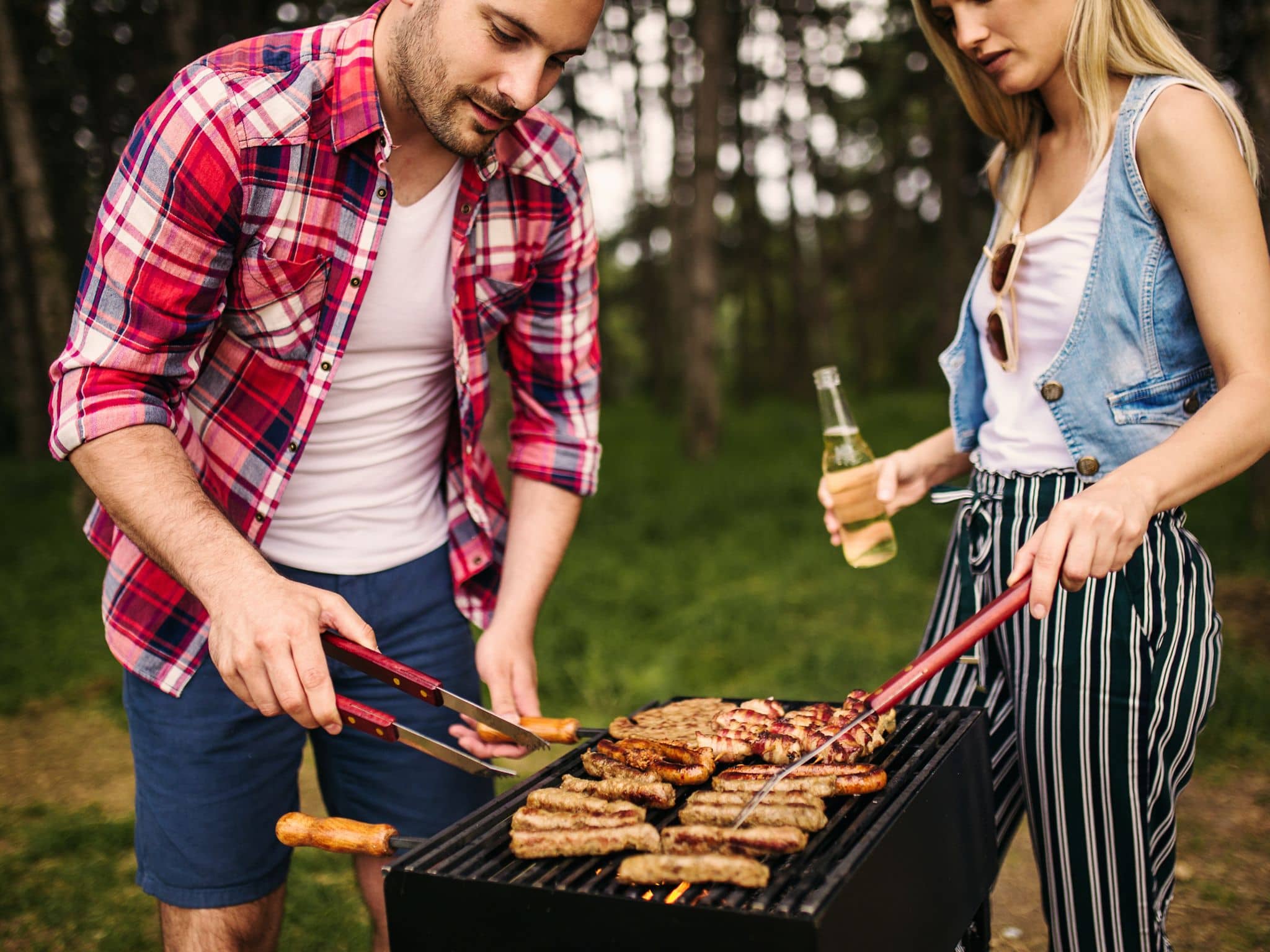 Fleischkonsum und Klimawandel: Paar grillt Fleisch auf einem Grill.