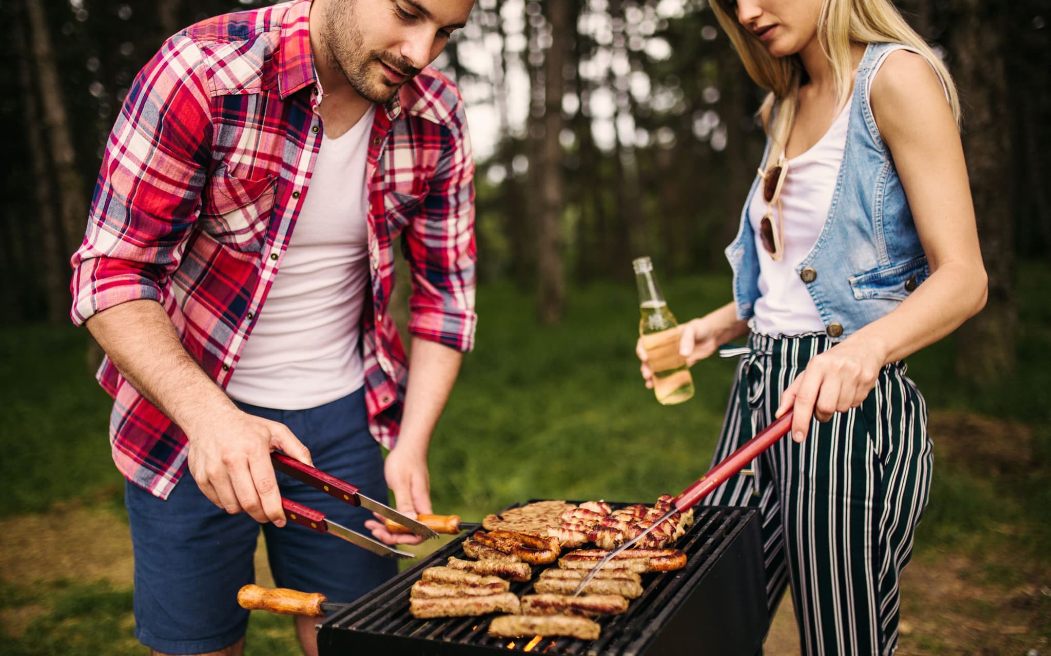 Fleischkonsum und Klimawandel: Paar grillt Fleisch auf einem Grill.