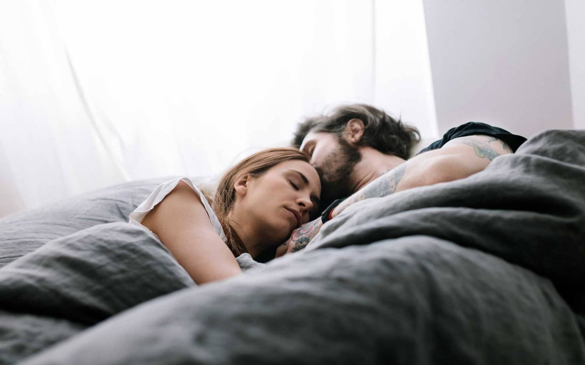 Junges Paar kuschelt verschlafen im Bett