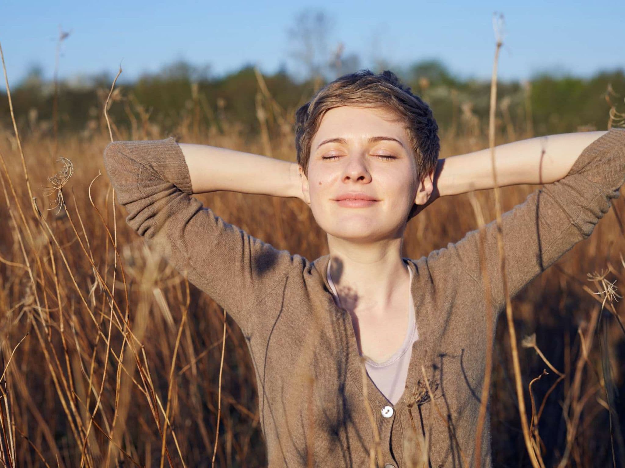Abendritual: Eine junge Frau steht mit geschlossenen Augen in einem Kornfeld.