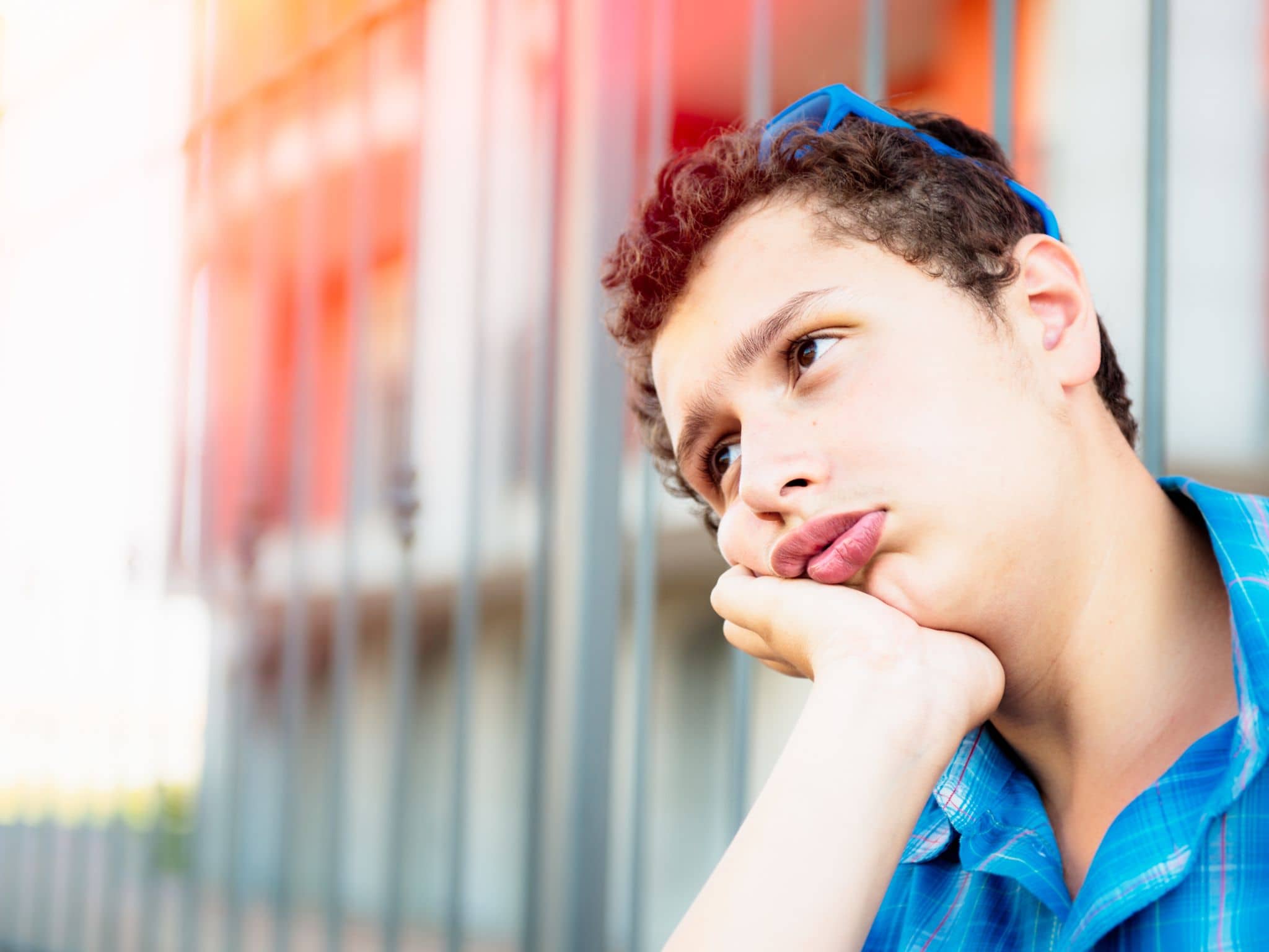 Testosteronmangel: Ein Junge im Teenageralter sitzt gelangweilt vor einer Wand und träumt